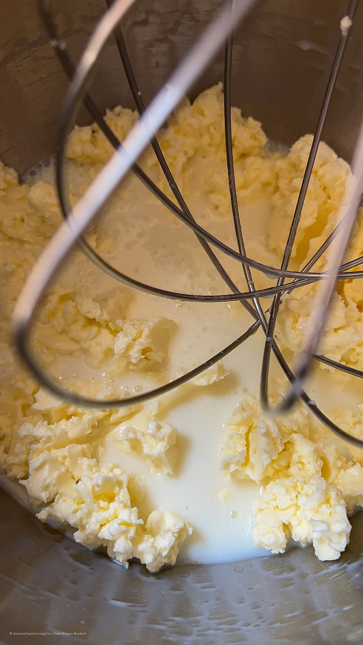 Butter and sugar mixture being creamed in a stand mixer bowl with wire whisk attachment.