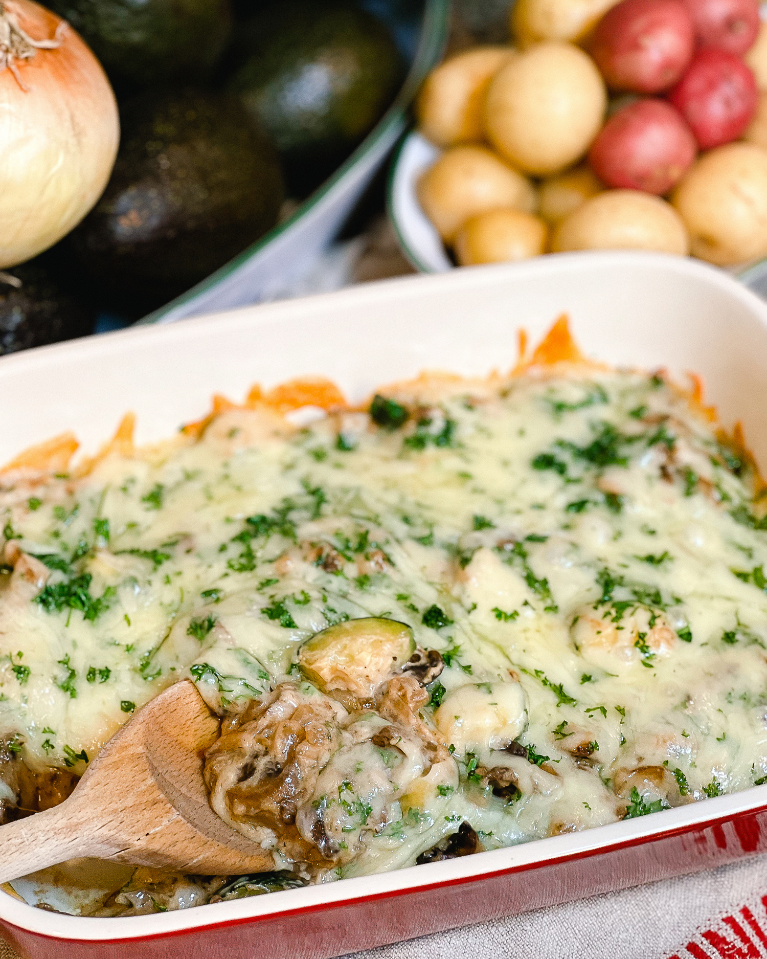 Creamy chicken casserole topped with melted cheese and fresh herbs in a white baking dish.