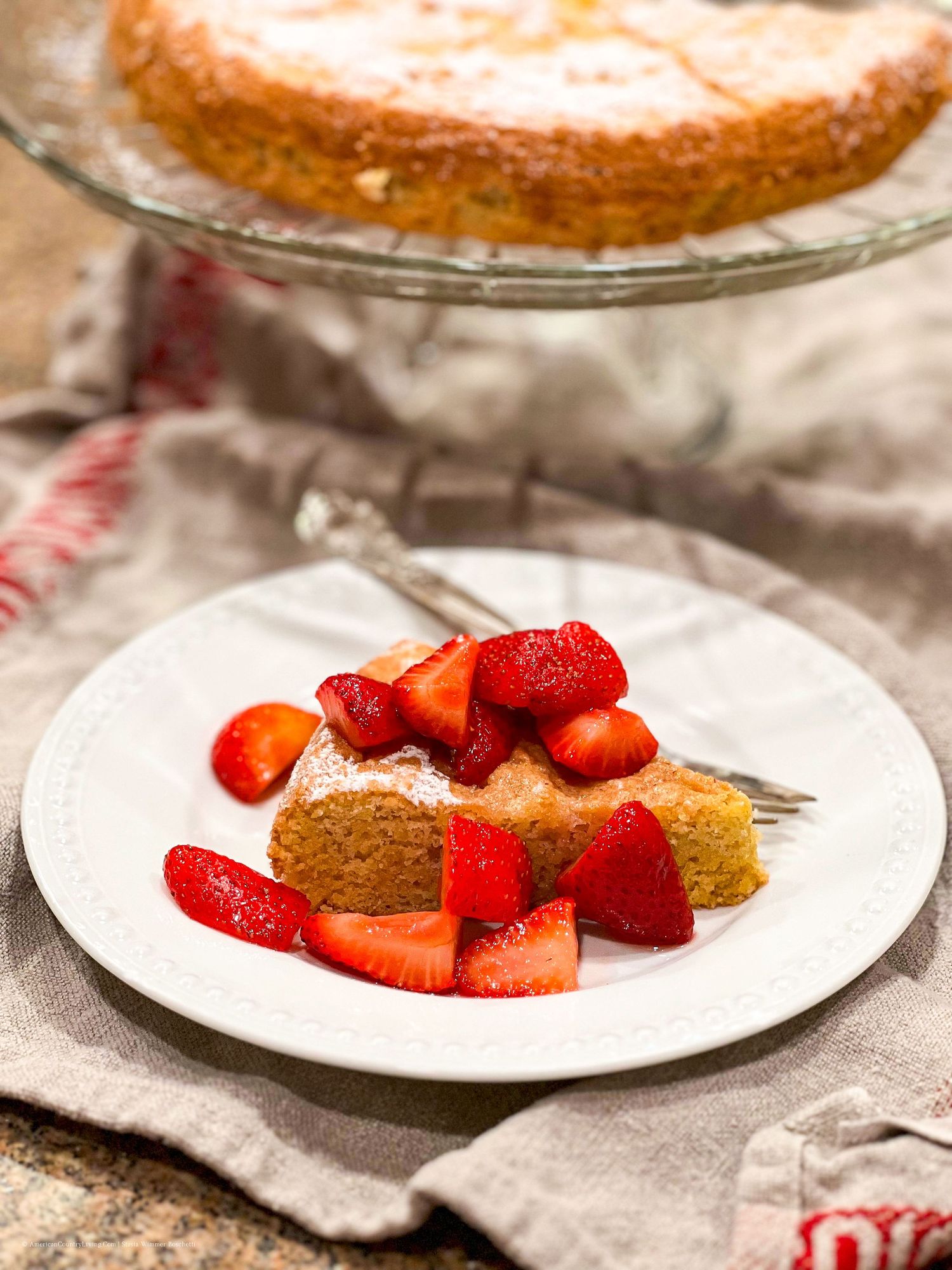 Sliced butter cake topped with fresh strawberries served on white plates.