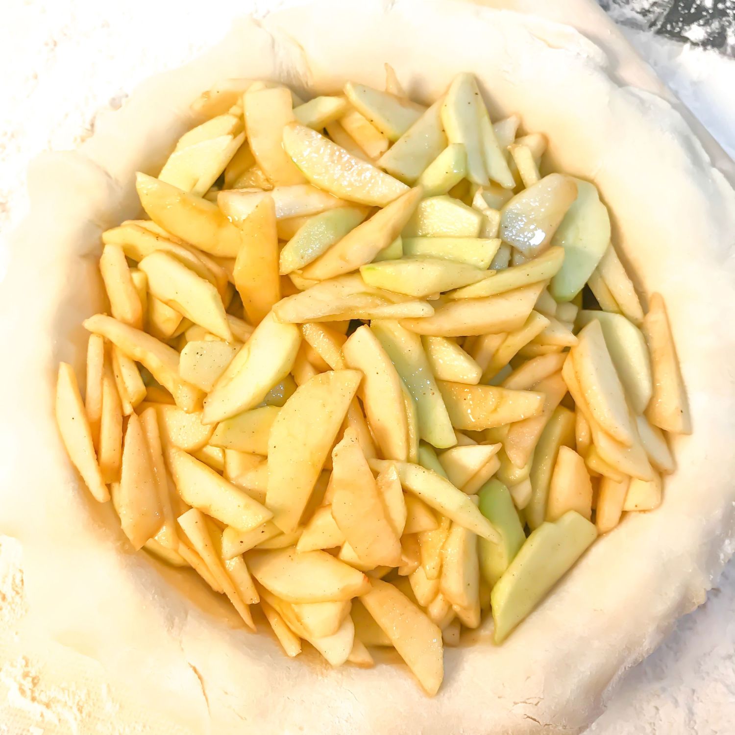 Fresh sliced yellow apples arranged in a pie crust before baking.