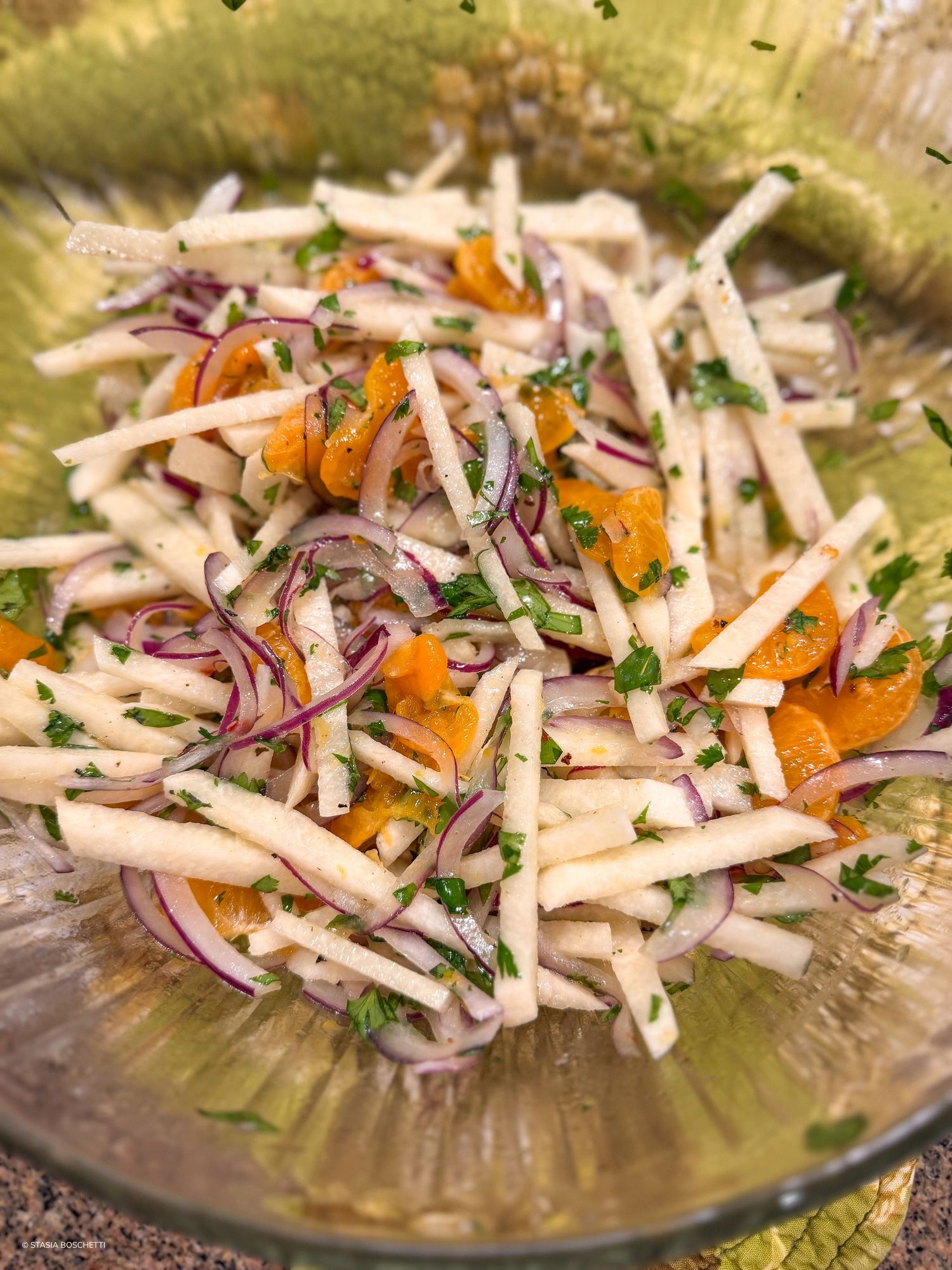 Fresh jicama salad with red onion, orange segments, and herbs in a glass bowl.