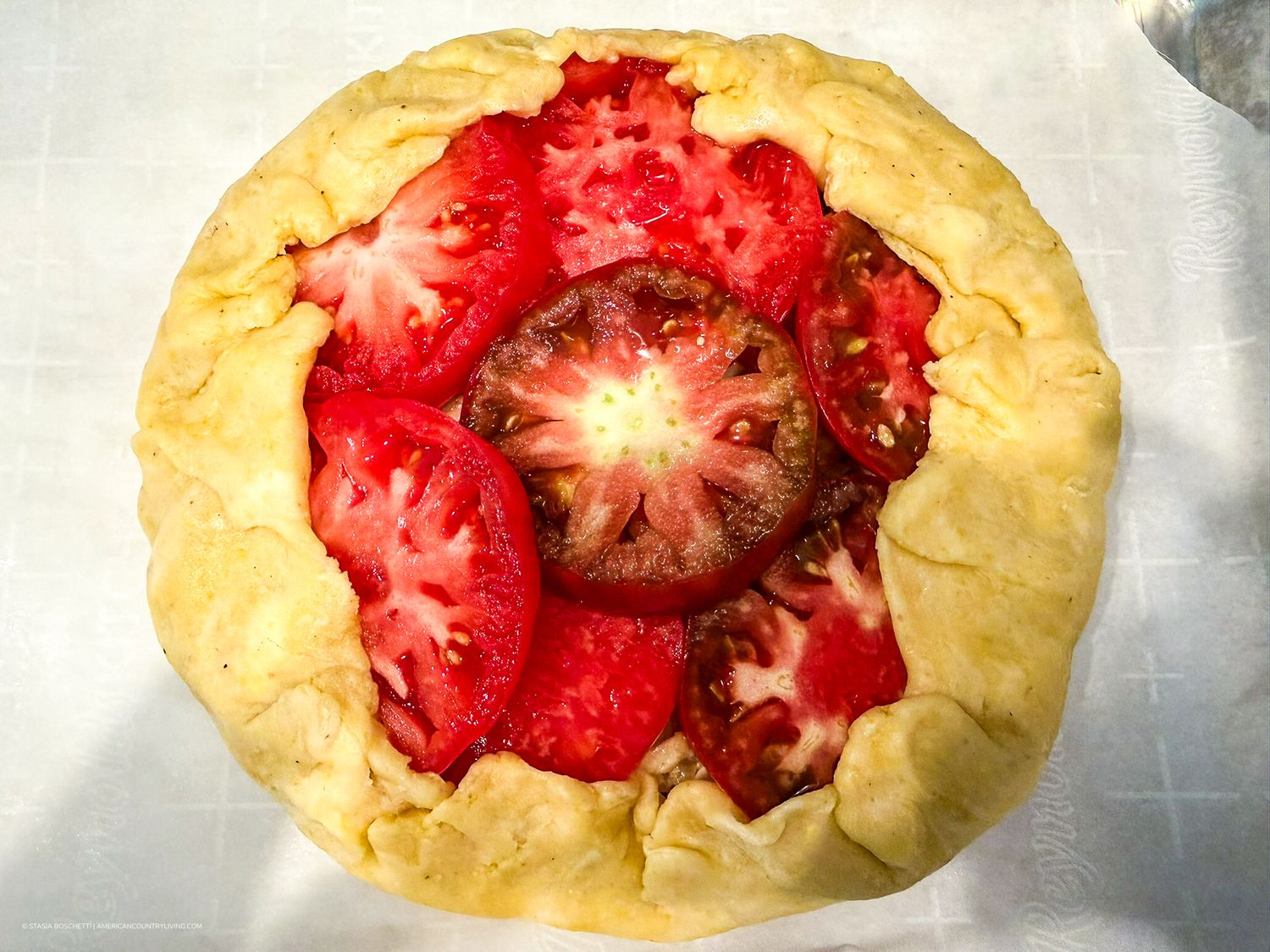 Rustic tomato galette with heirloom and red tomatoes on a flaky golden pastry crust, baked to perfection.