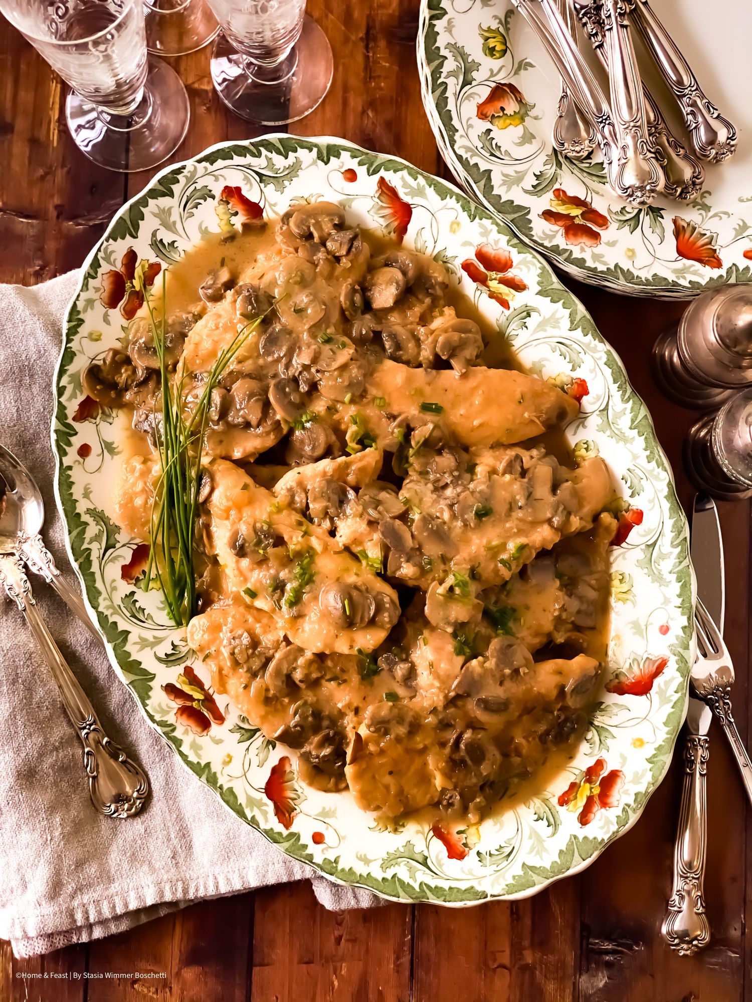 Rustic chicken marsala with mushroom sauce plated on decorative china with fresh herbs.
