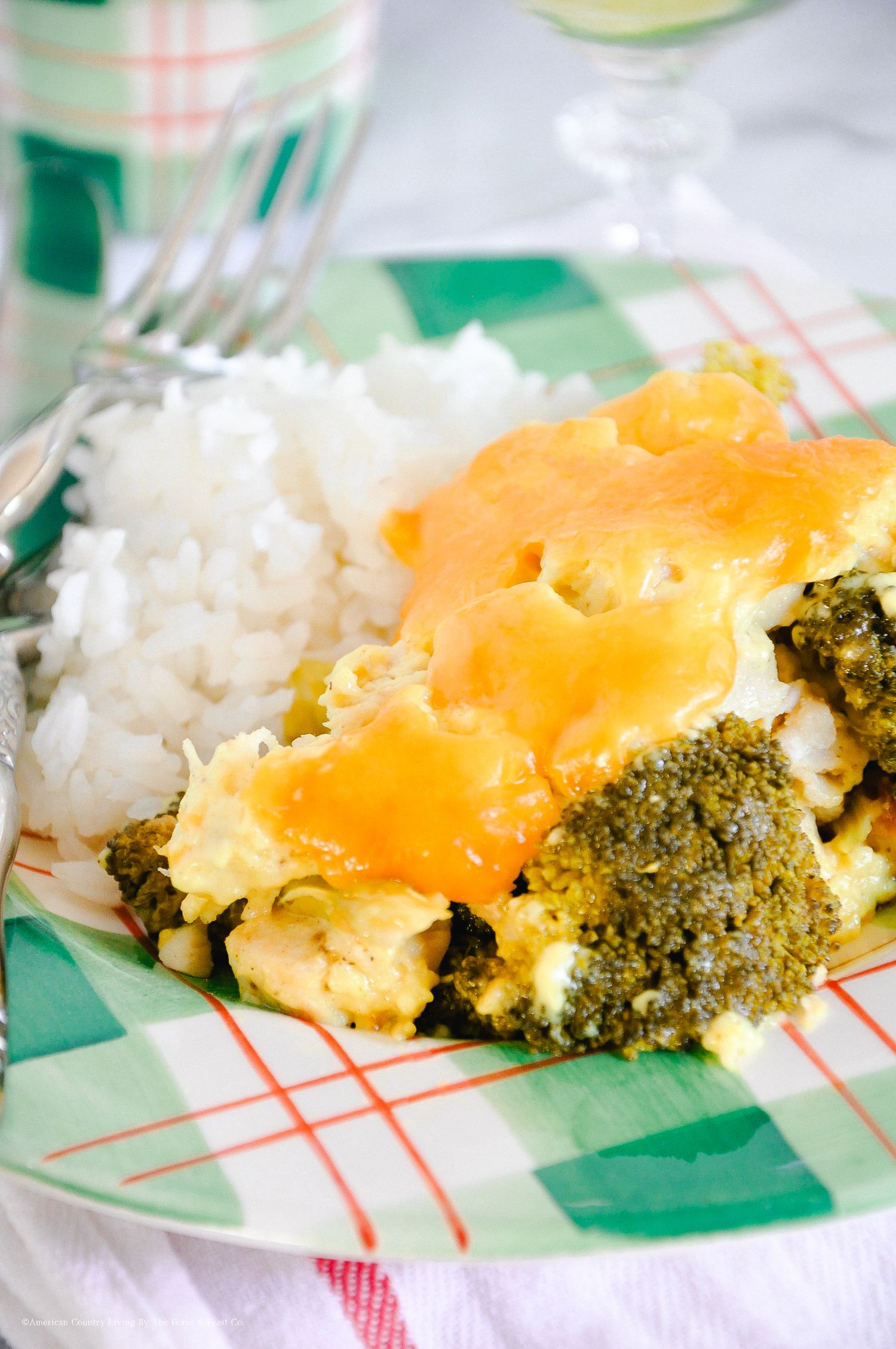 Broccoli and cheese casserole with white rice on a green and white checkered cloth.