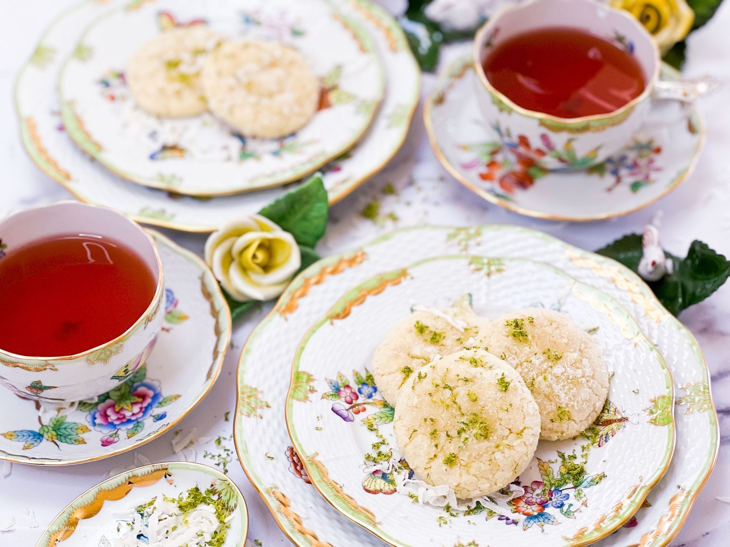 Tea party setting with ornate floral plates and delicate desserts.