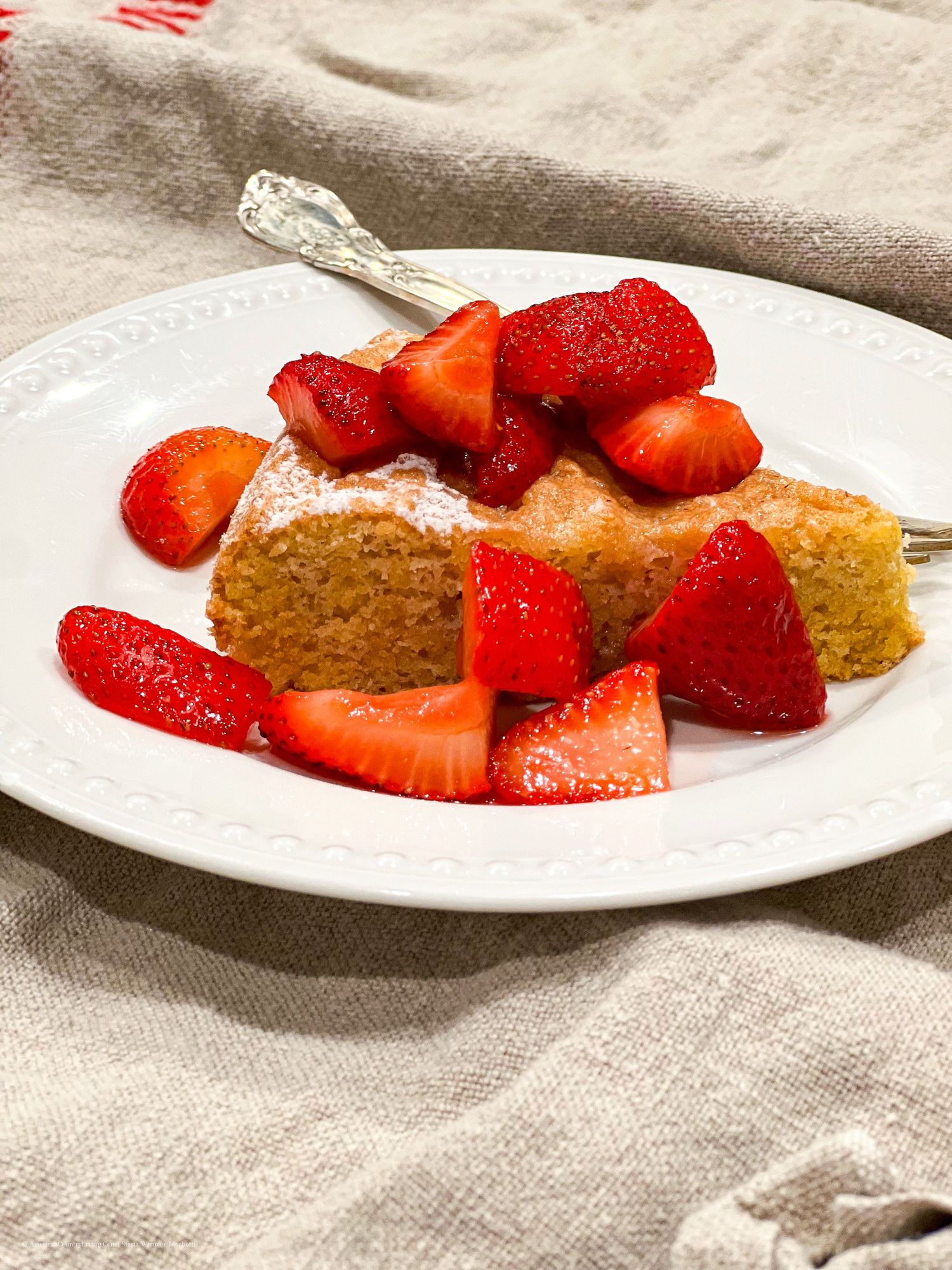 Homemade pound cake served with bright red strawberries on white dinnerware.