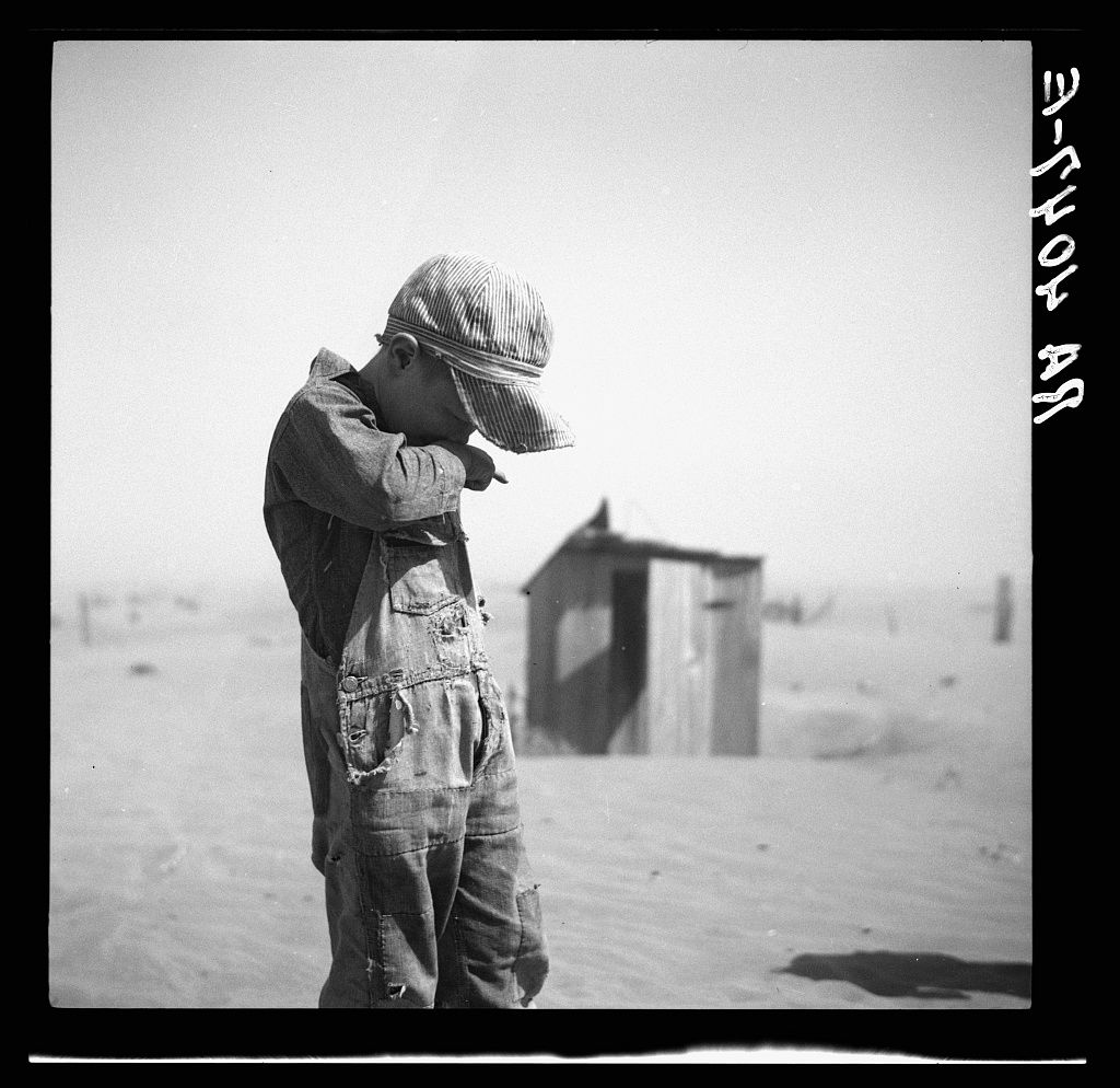 A sequence of black and white photographs showing abandoned farmhouses and buildings amid sand dunes in a barren landscape.