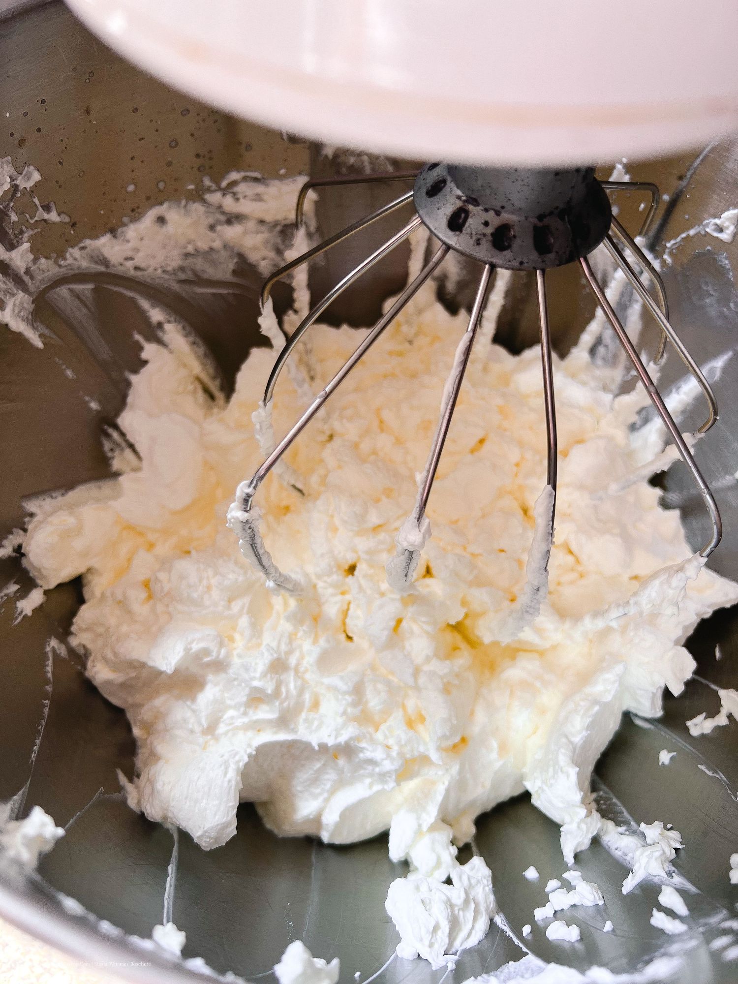 Stand mixer whipping butter and sugar together into a light and fluffy mixture.