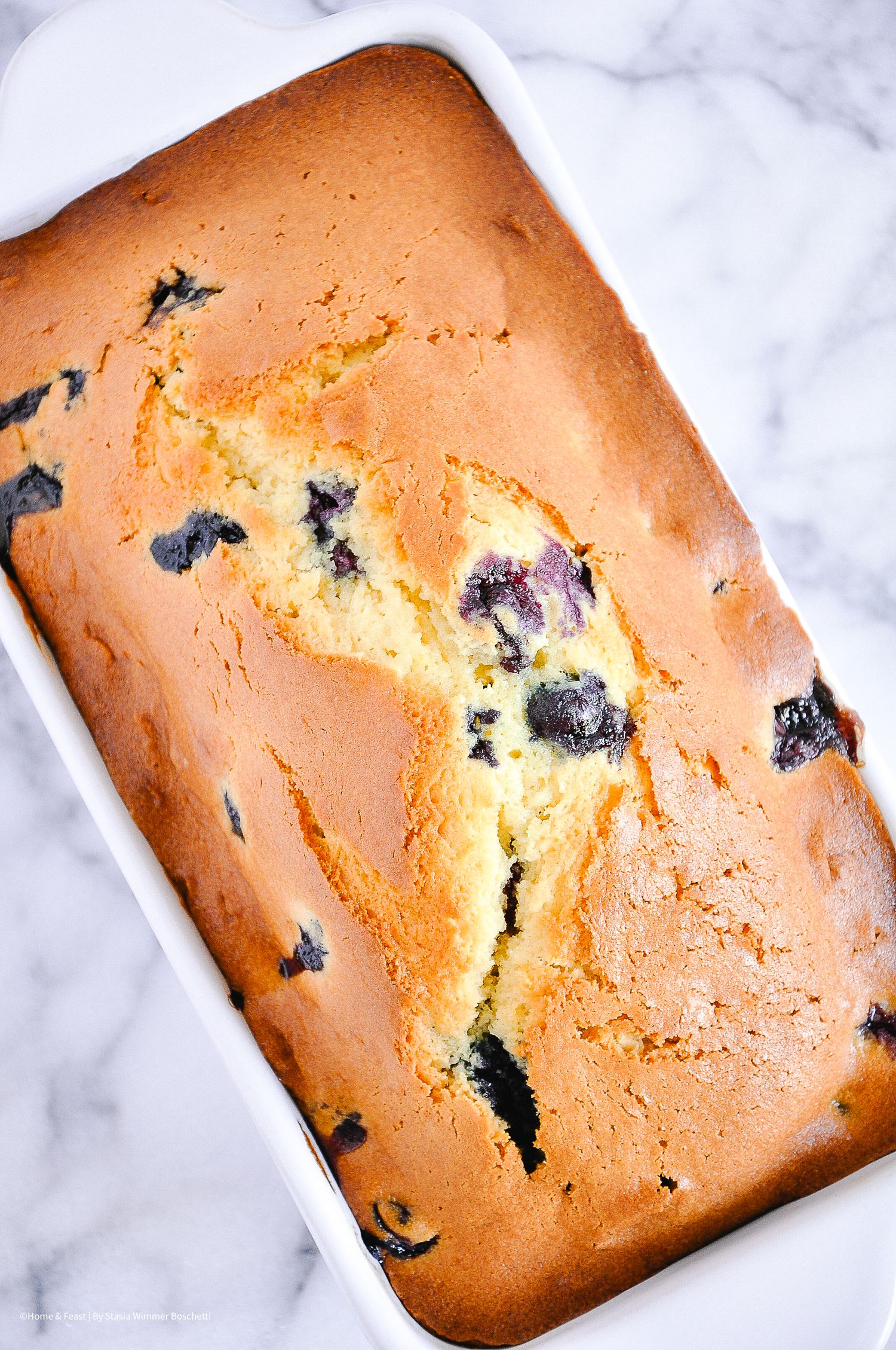 Golden brown blueberry pound cake with dark berries visible throughout.