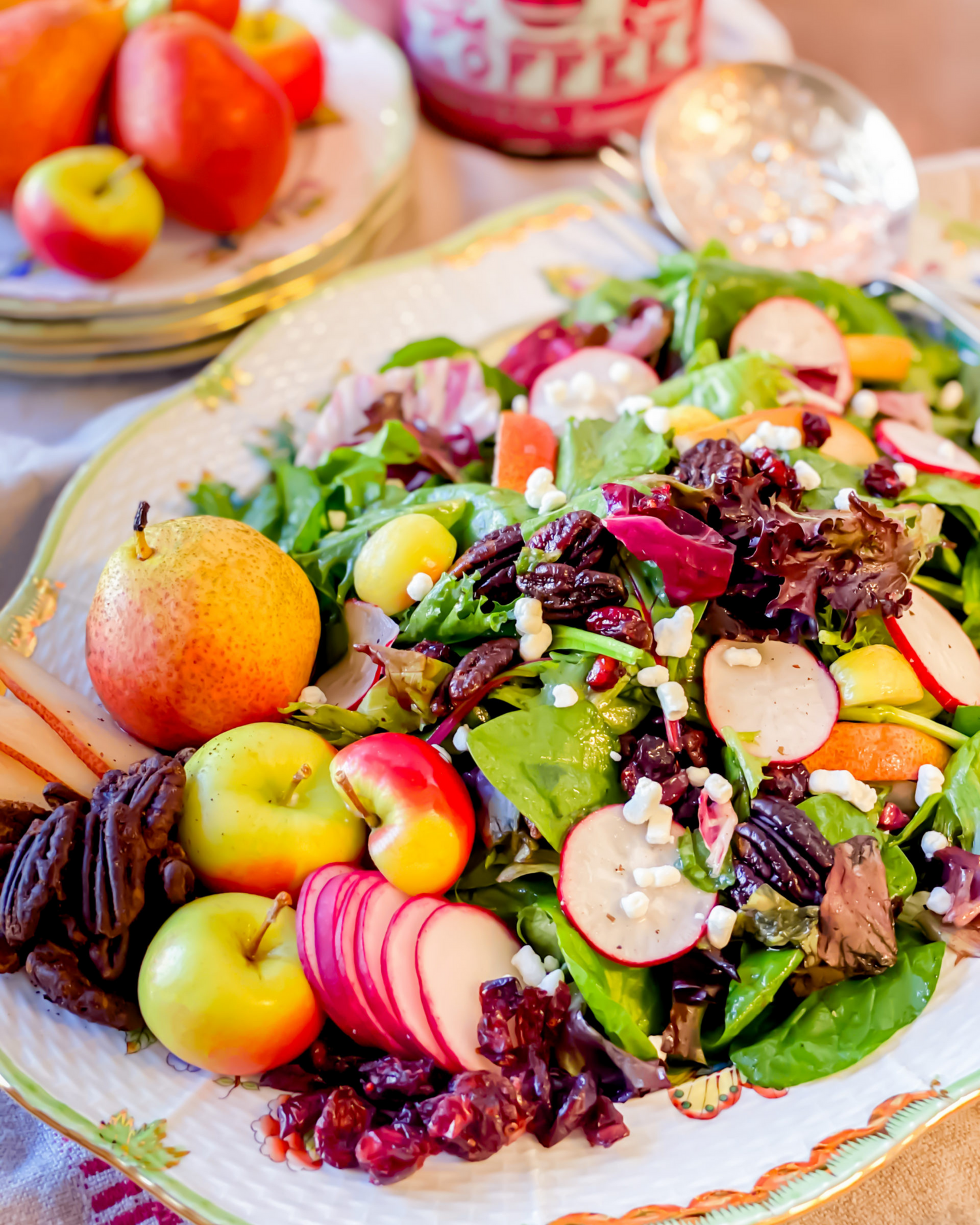 Fresh autumn salad with apples, cranberries, and pecans served alongside seasonal fruits.