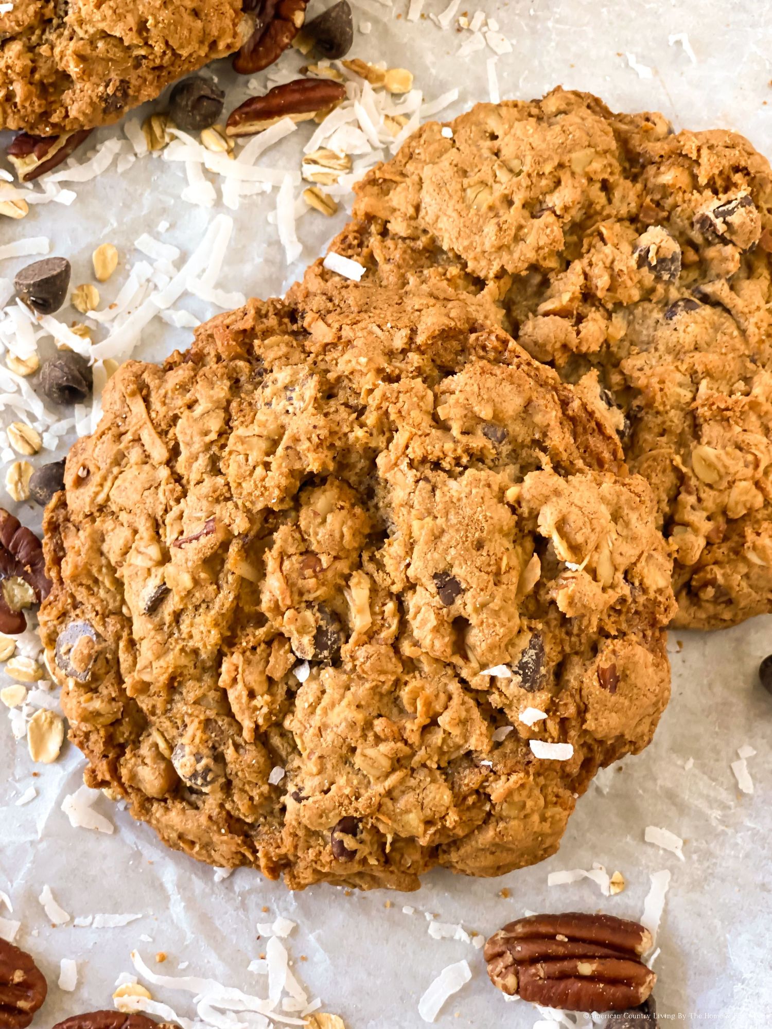 Freshly baked oatmeal cookies with pecans and coconut flakes on parchment paper.