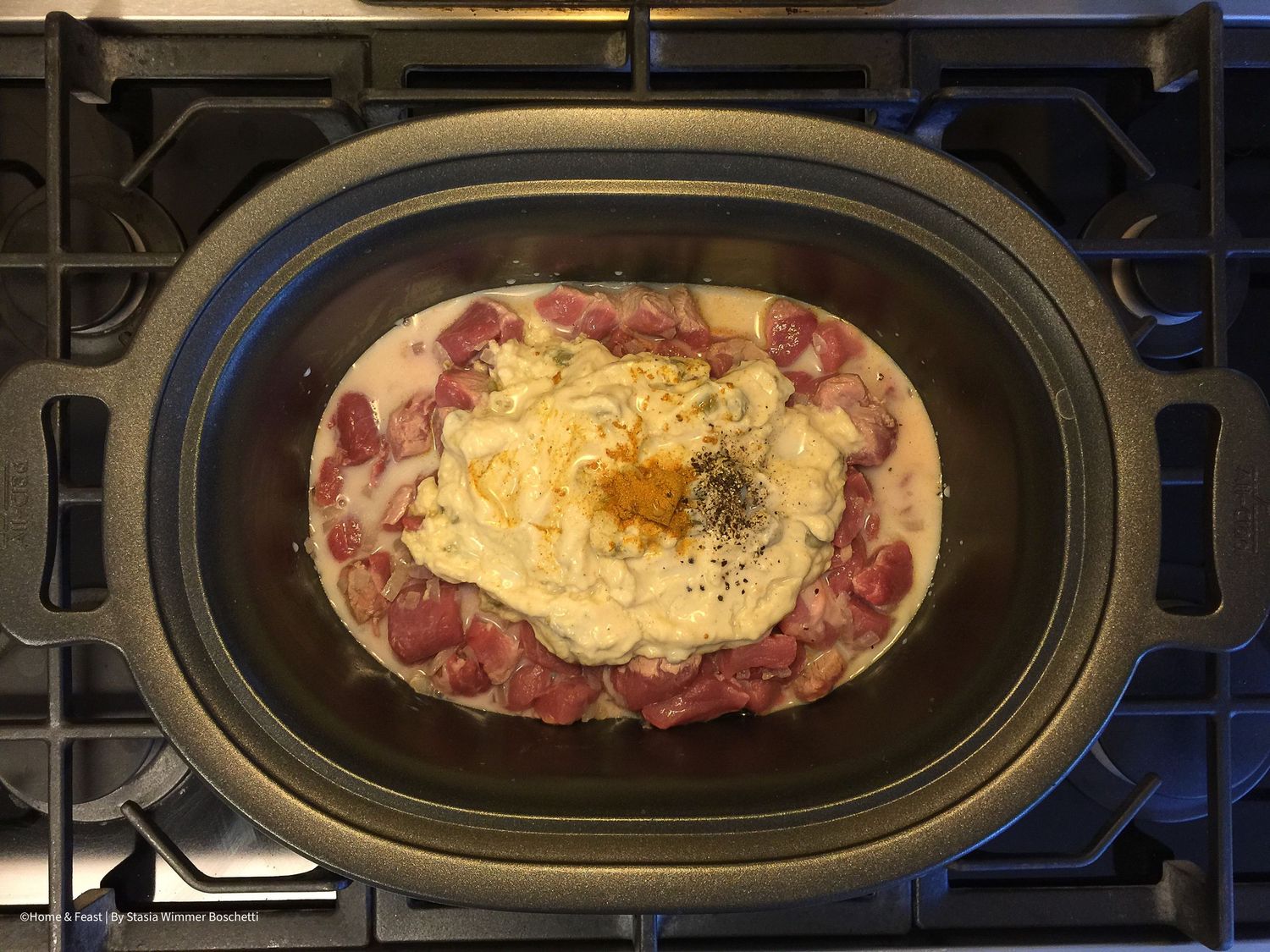 Creamy sauce and seasonings mixed with meat in oval cooking dish.