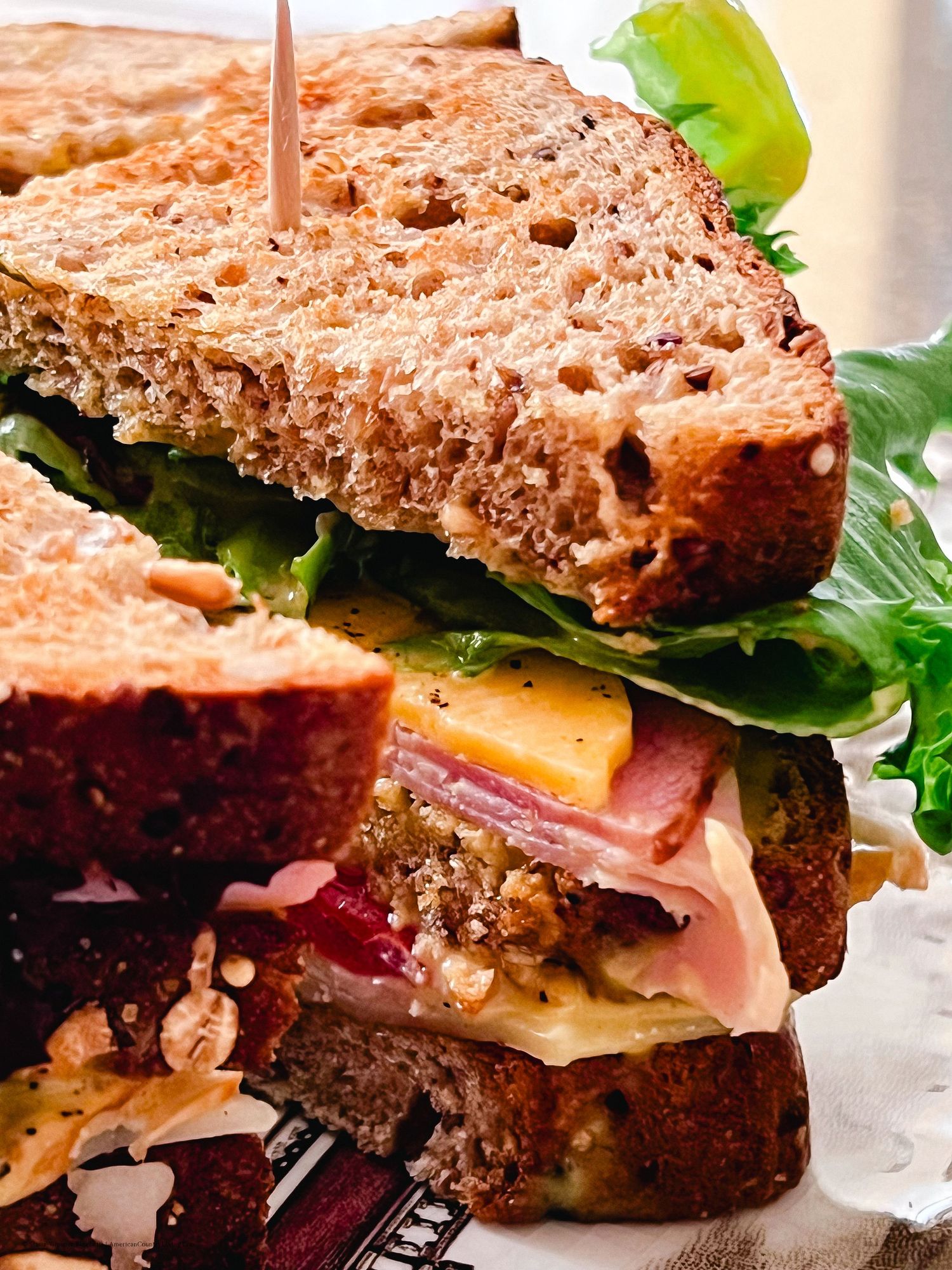 Hearty sandwich with layers of meat, cheese and fresh lettuce on rustic whole grain bread.