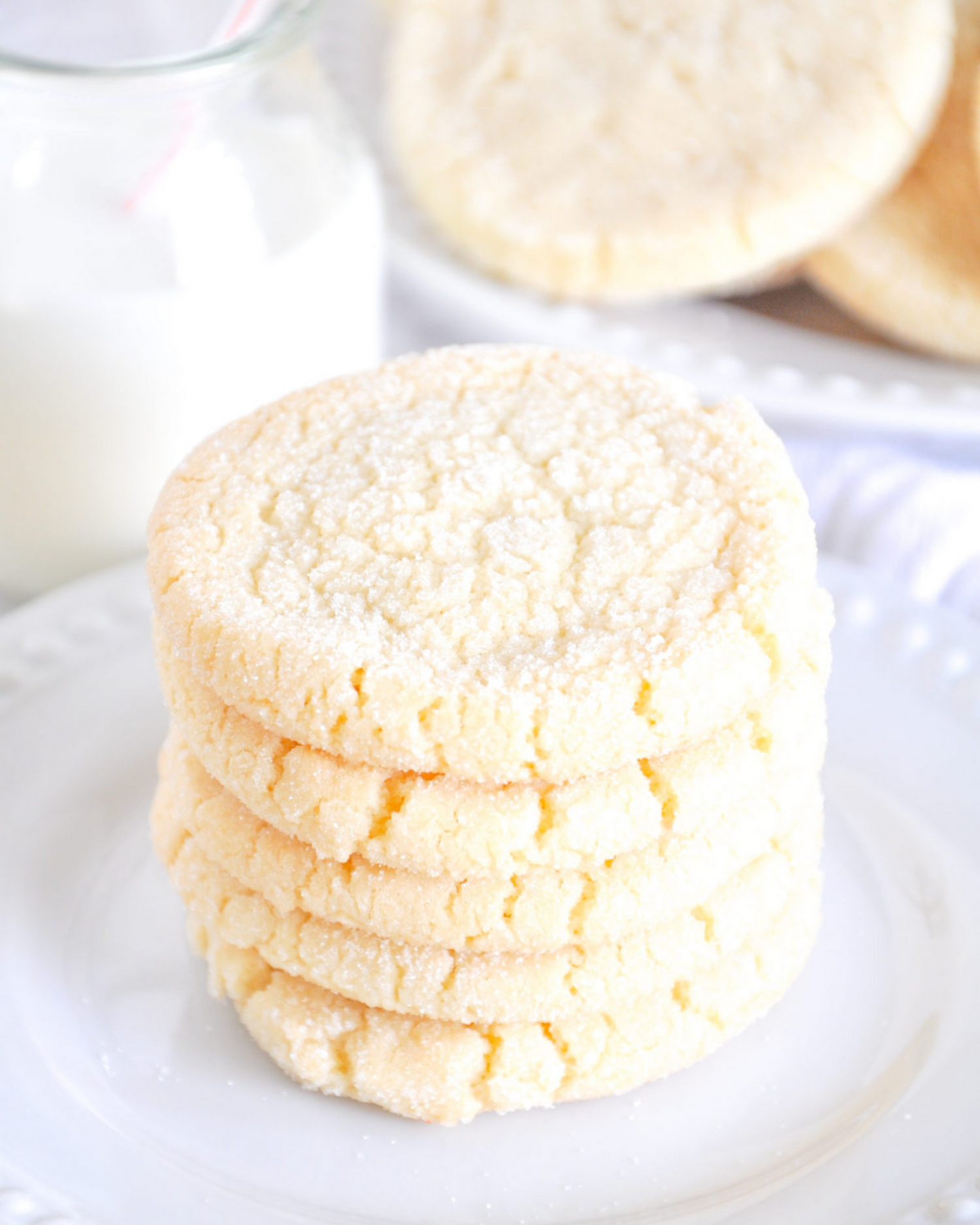 Stack of homemade sugar cookies with crackled surfaces on a white plate.