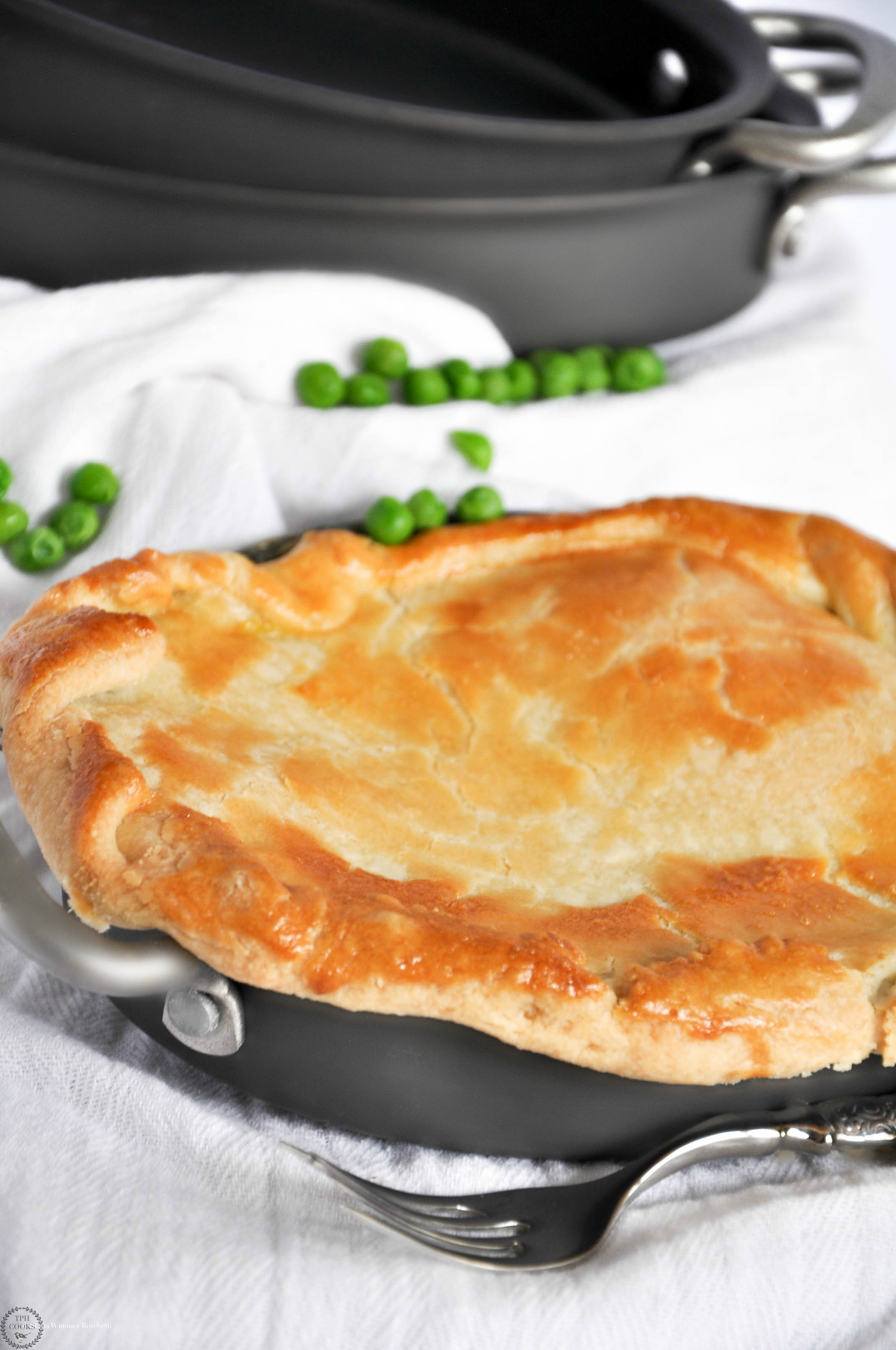 Golden brown pie crust baked to perfection with peas visible on the side.