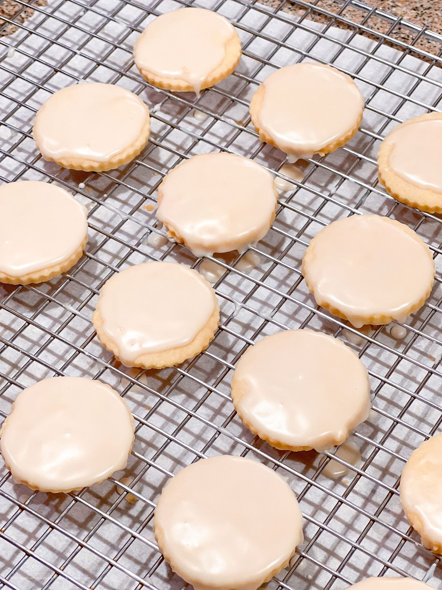 Heart-shaped cookies with pale pink frosting laid out on a metal cooling rack.
