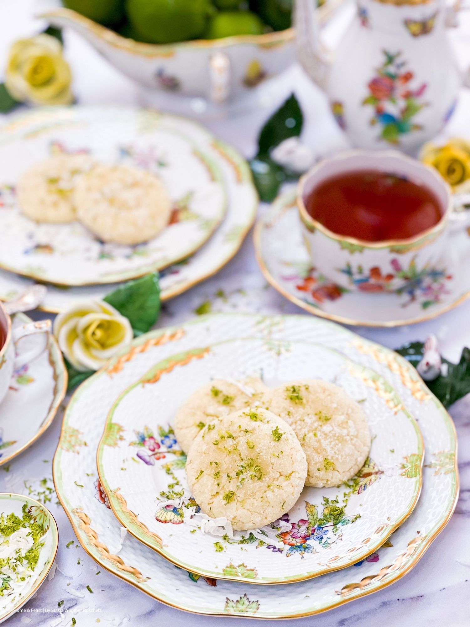 Floral china plates arranged with delicate pastries and tea cups.