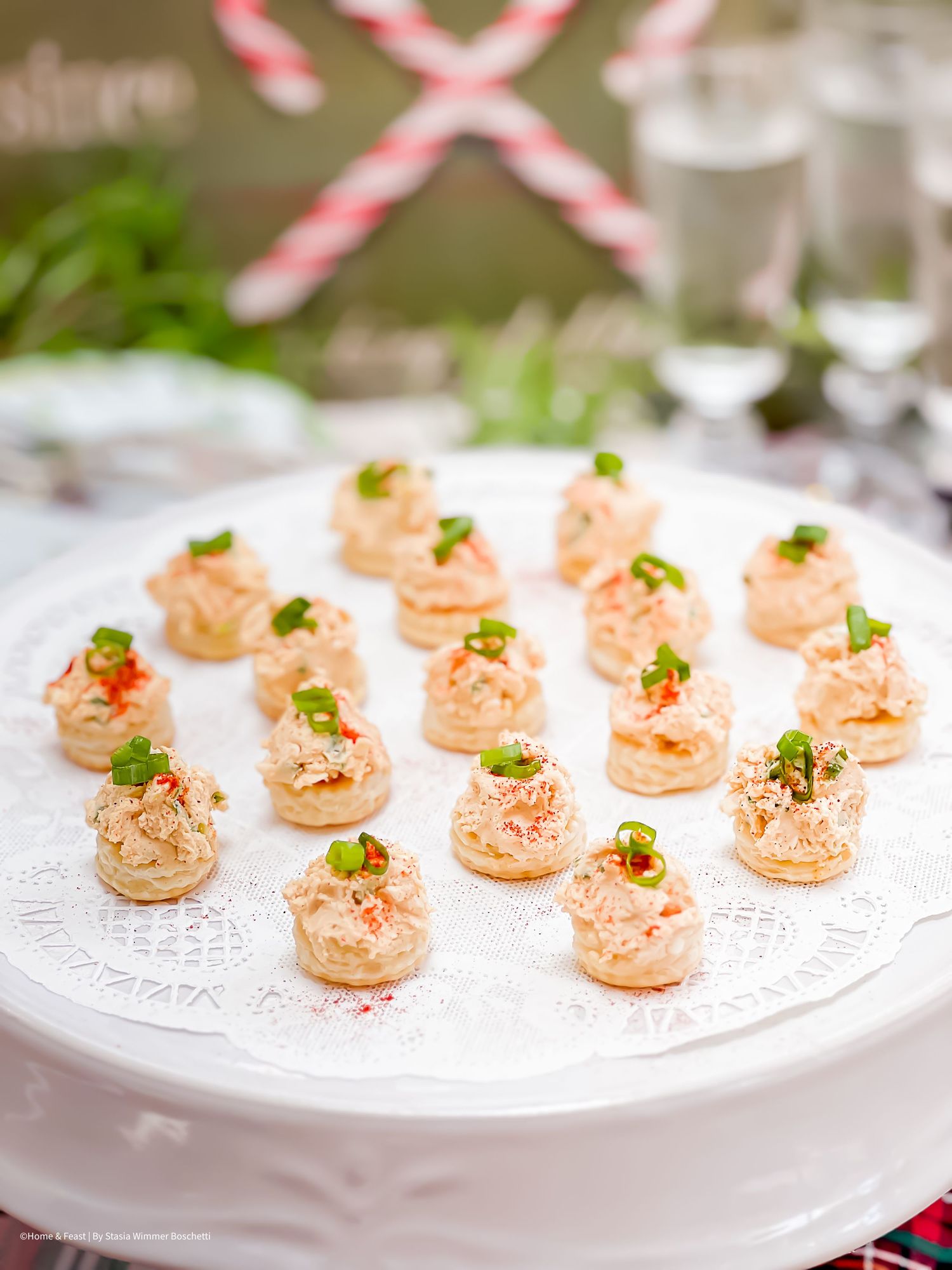 Small pink appetizers with green garnish arranged on white serving plates for an elegant presentation.
