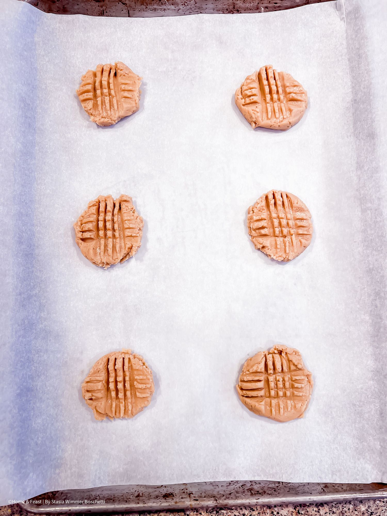 Freshly baked peanut butter cookies cooling on a wire rack with classic crosshatch fork marks on top.