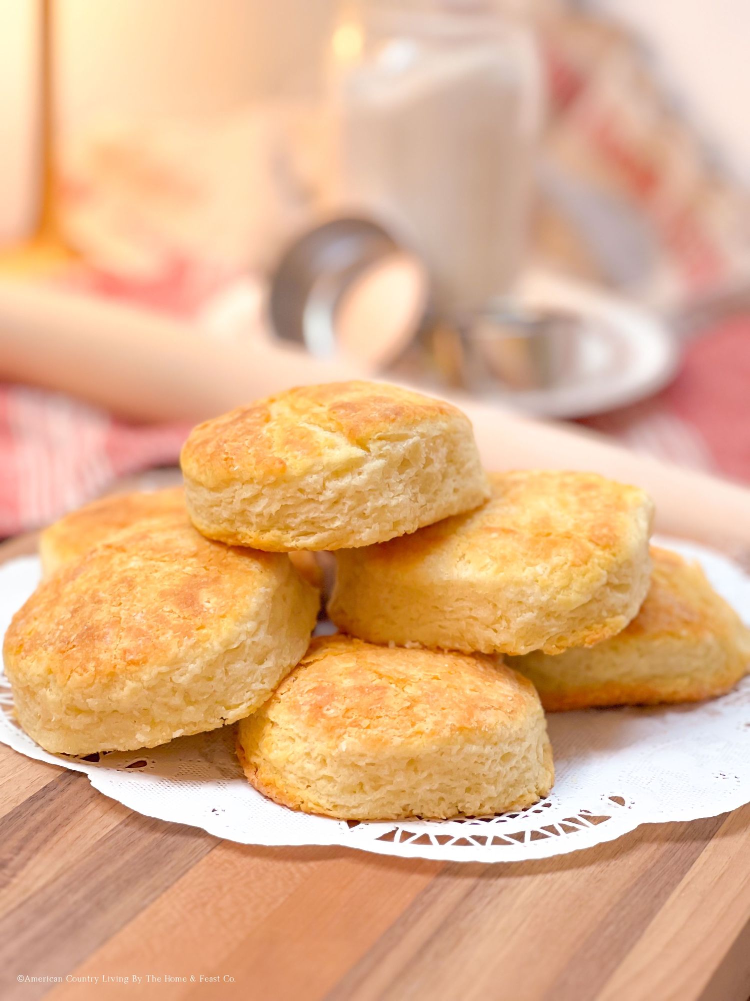 Golden buttermilk biscuits arranged on a white doily plate with a soft focus background.