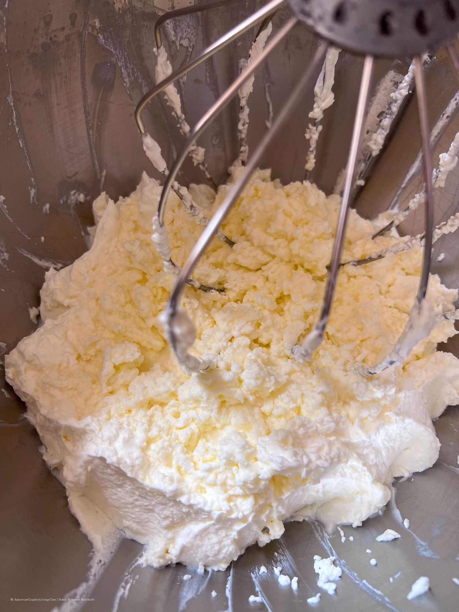 Butter and sugar mixture being whipped to a fluffy consistency in a stand mixer.
