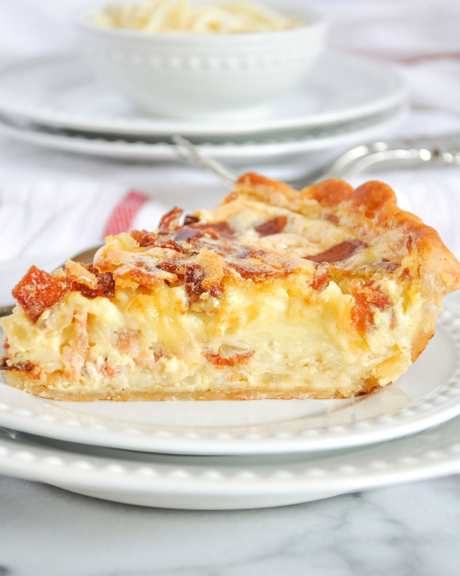 Slices of homemade quiche with flaky crust served on white plates.