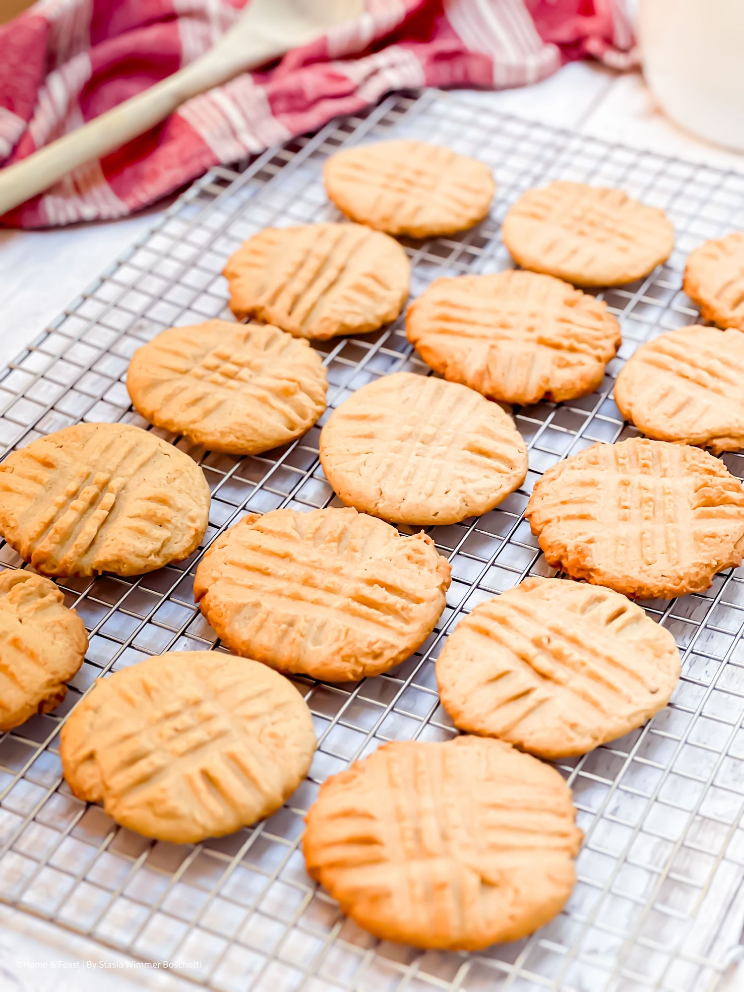 Golden peanut butter cookies with crosshatch marks cooling on a wire rack, perfect homemade baked treats.