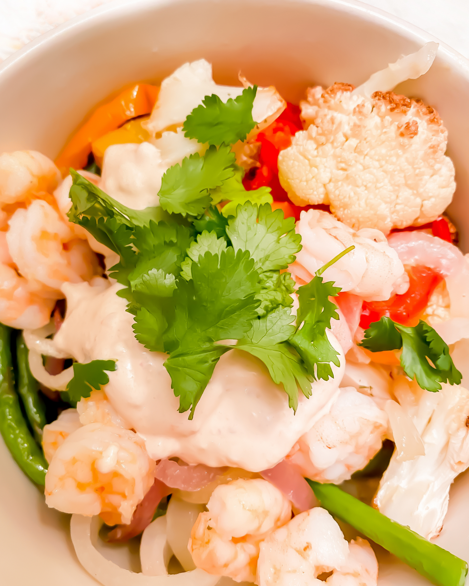 Cooked shrimp salad garnished with fresh cilantro and red peppers.