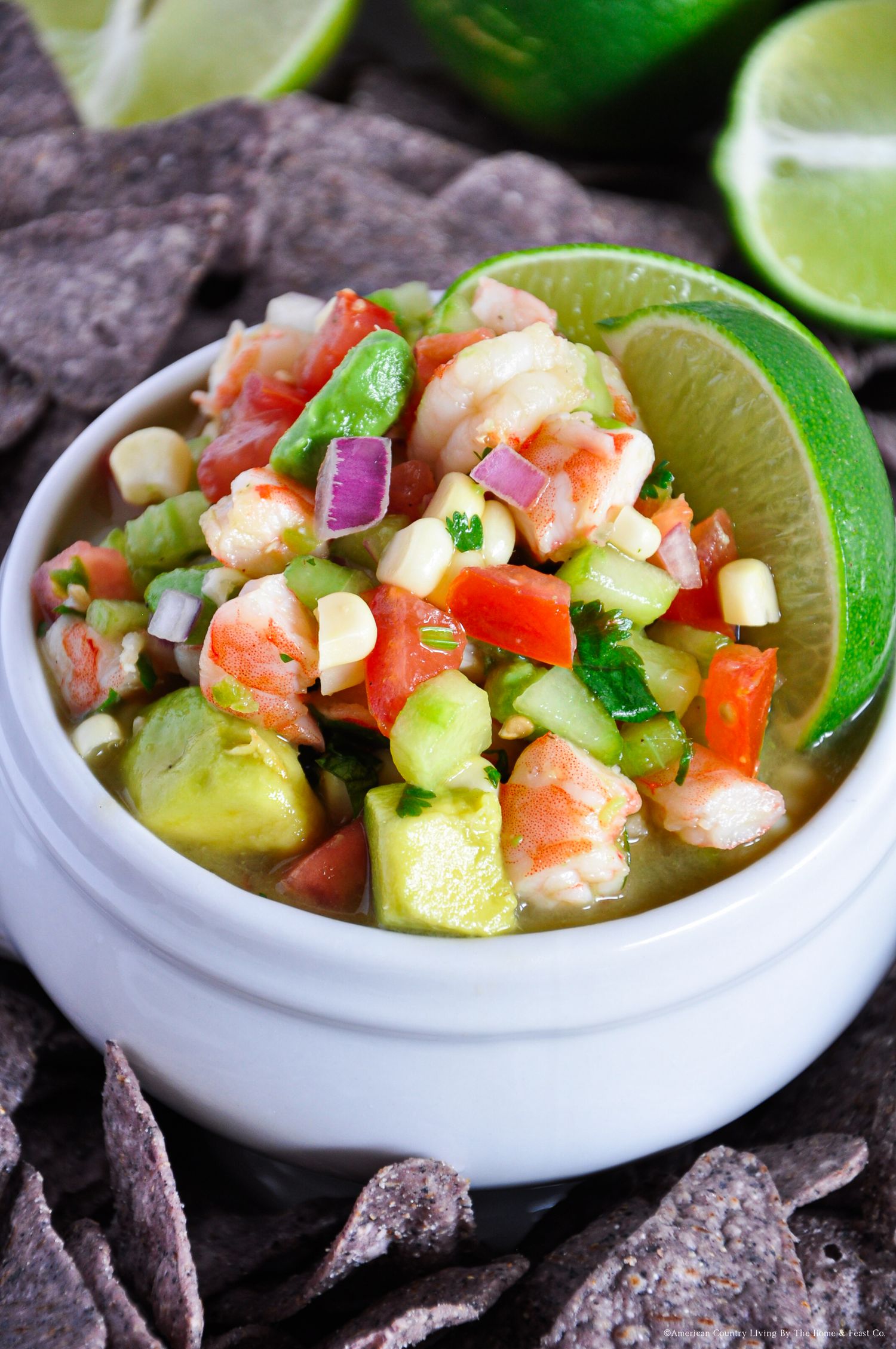 Fresh shrimp ceviche with avocado, lime and vegetables served in white bowls with tortilla chips.