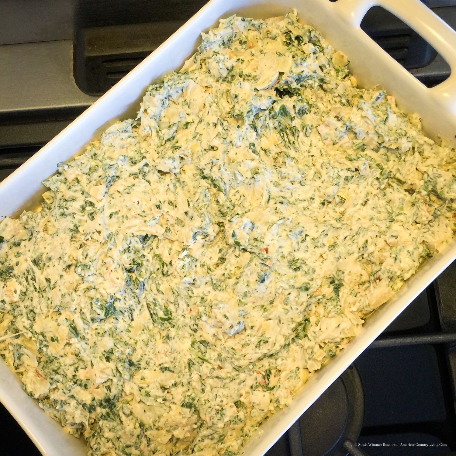 Creamy spinach artichoke dip in a white baking dish, ready to be baked to golden perfection.