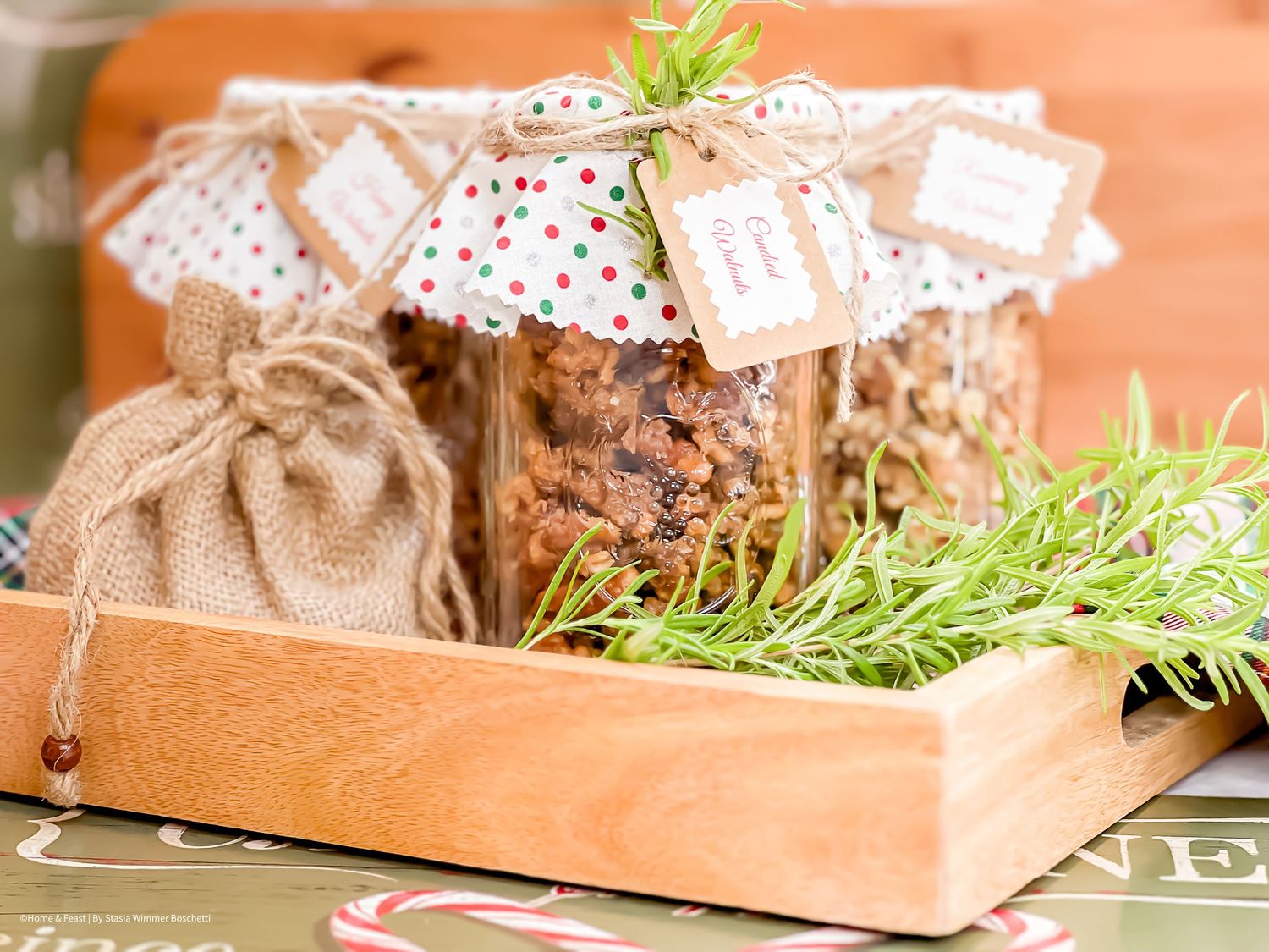 Rustic wooden tray holding mason jars of homemade granola with decorative fabric tops.