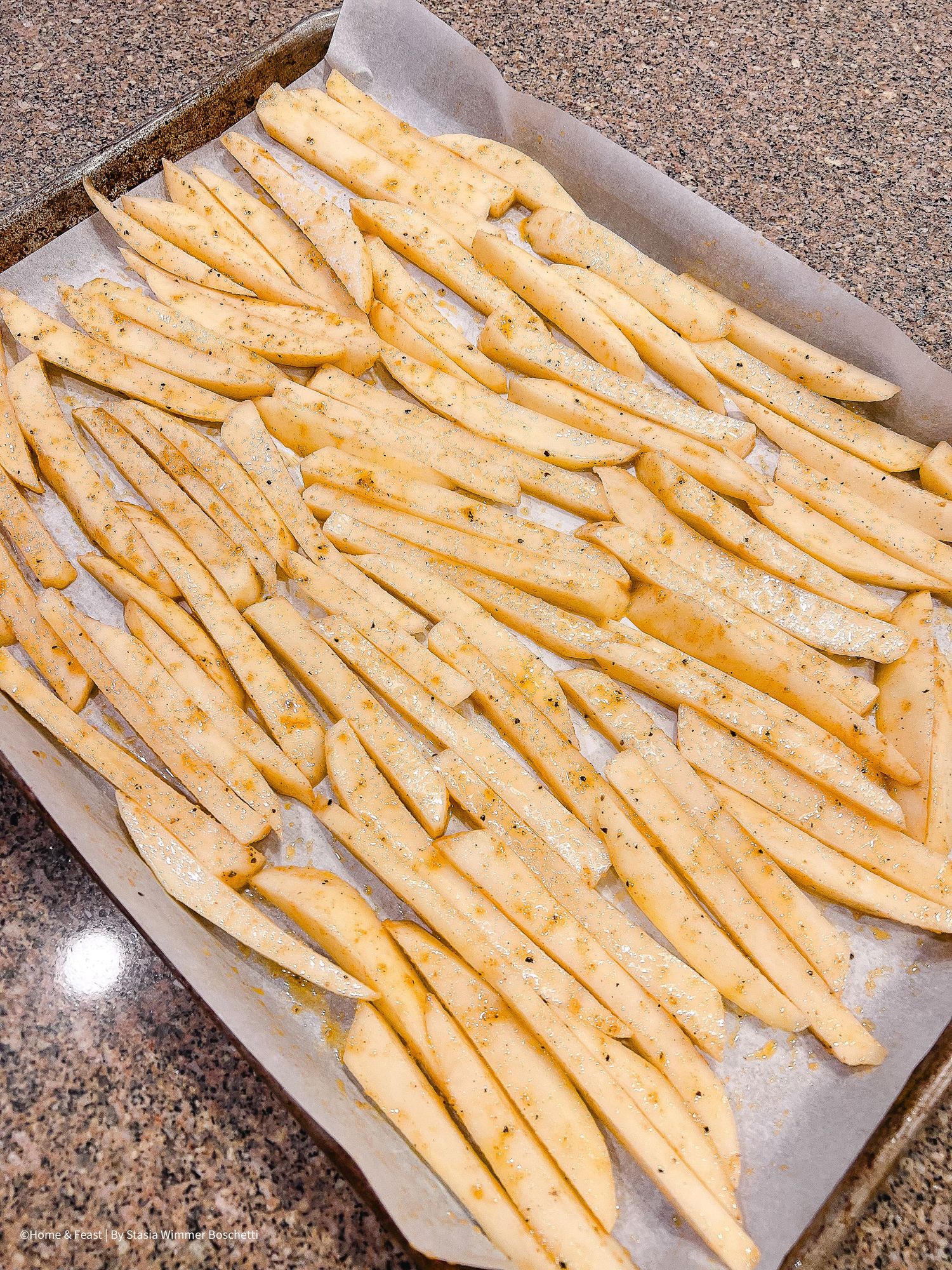 Raw cut french fries arranged on parchment paper ready for baking.