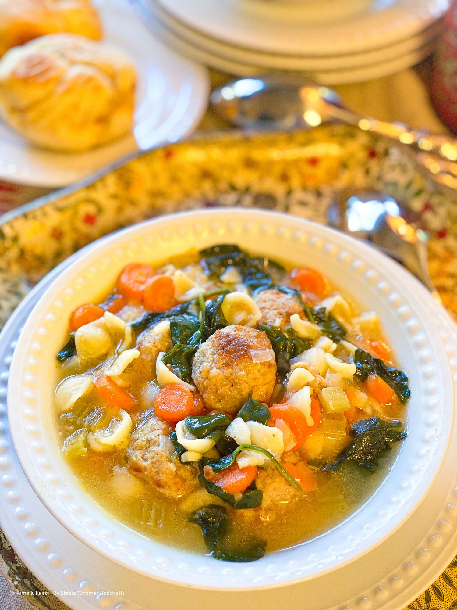 Steaming bowl of homemade vegetable soup with tender vegetables in clear broth on white plate.