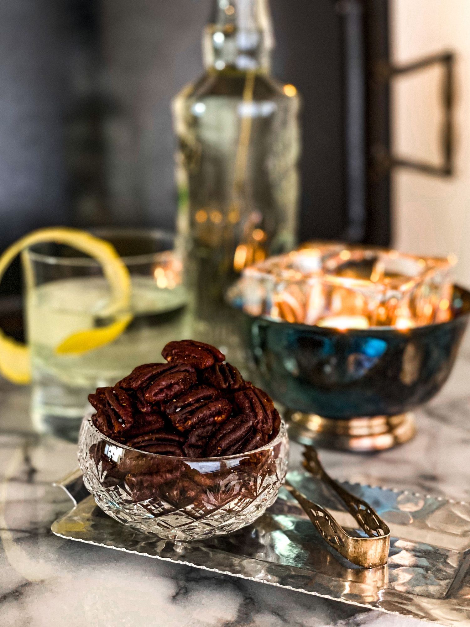 Spiced pecans served in an elegant crystal bowl on marble surface.