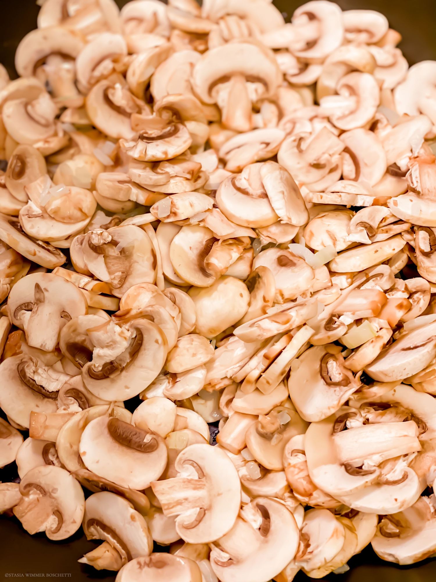 Thinly sliced raw mushrooms arranged in neat rows showing their pale cream color.