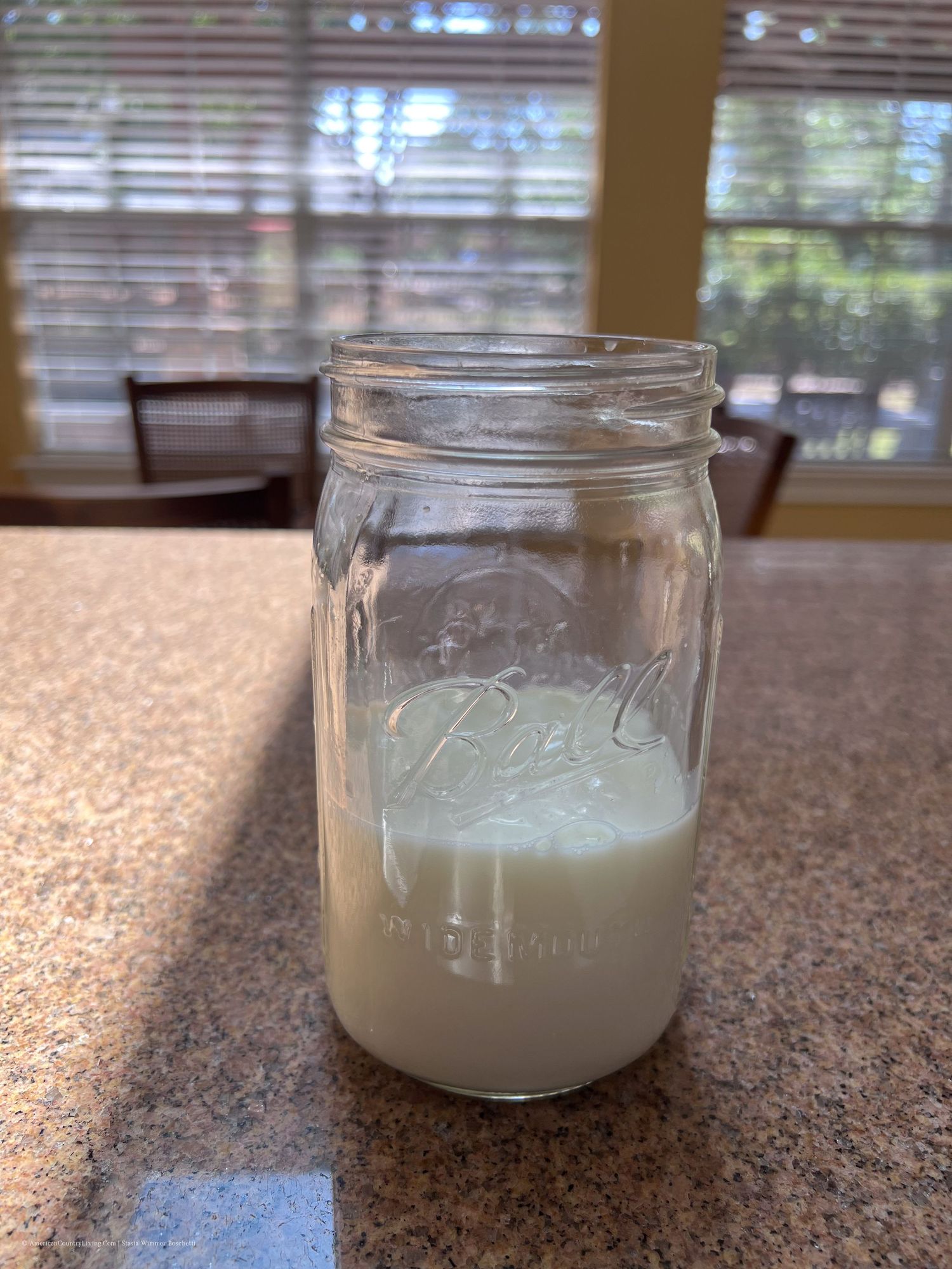 Mason jars filled with fresh cream sitting on a granite countertop.