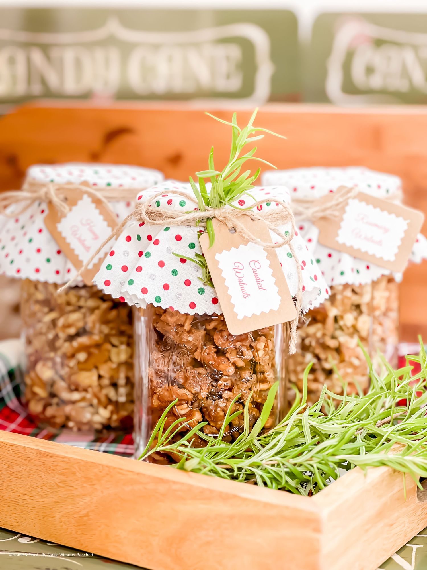 Homemade granola in decorated glass jars with polka dot covers displayed on a wooden tray.