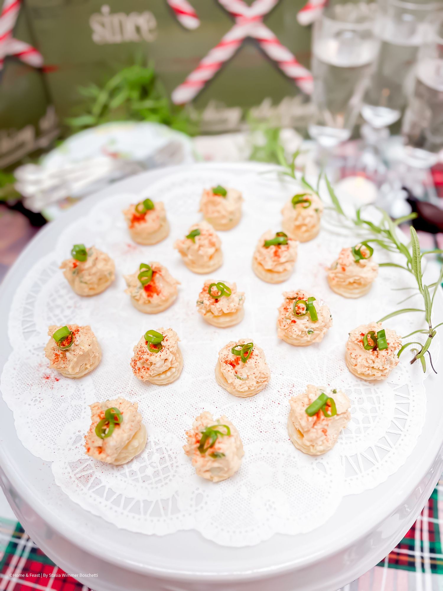 Elegant appetizers with pink mousse filling garnished with herbs on a white serving platter.
