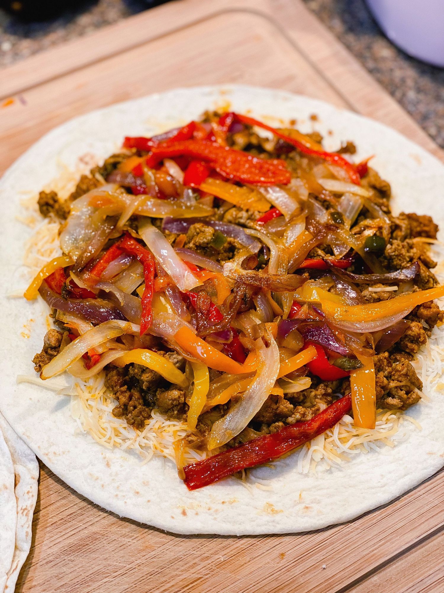 Beef fajita filling with bell peppers and onions served on tortilla with melted cheese.