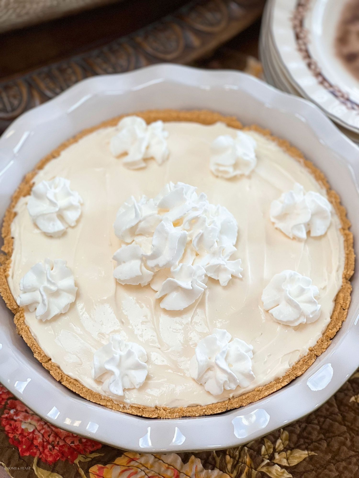 No-bake cream pie with whipped topping in fluted ceramic dish with graham cracker crust.