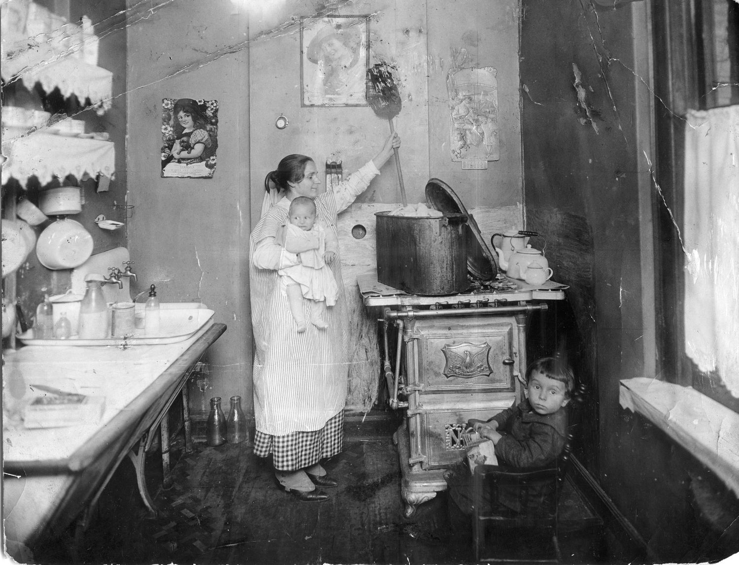 A vintage black and white photograph shows a narrow bathroom interior with worn walls and basic fixtures.