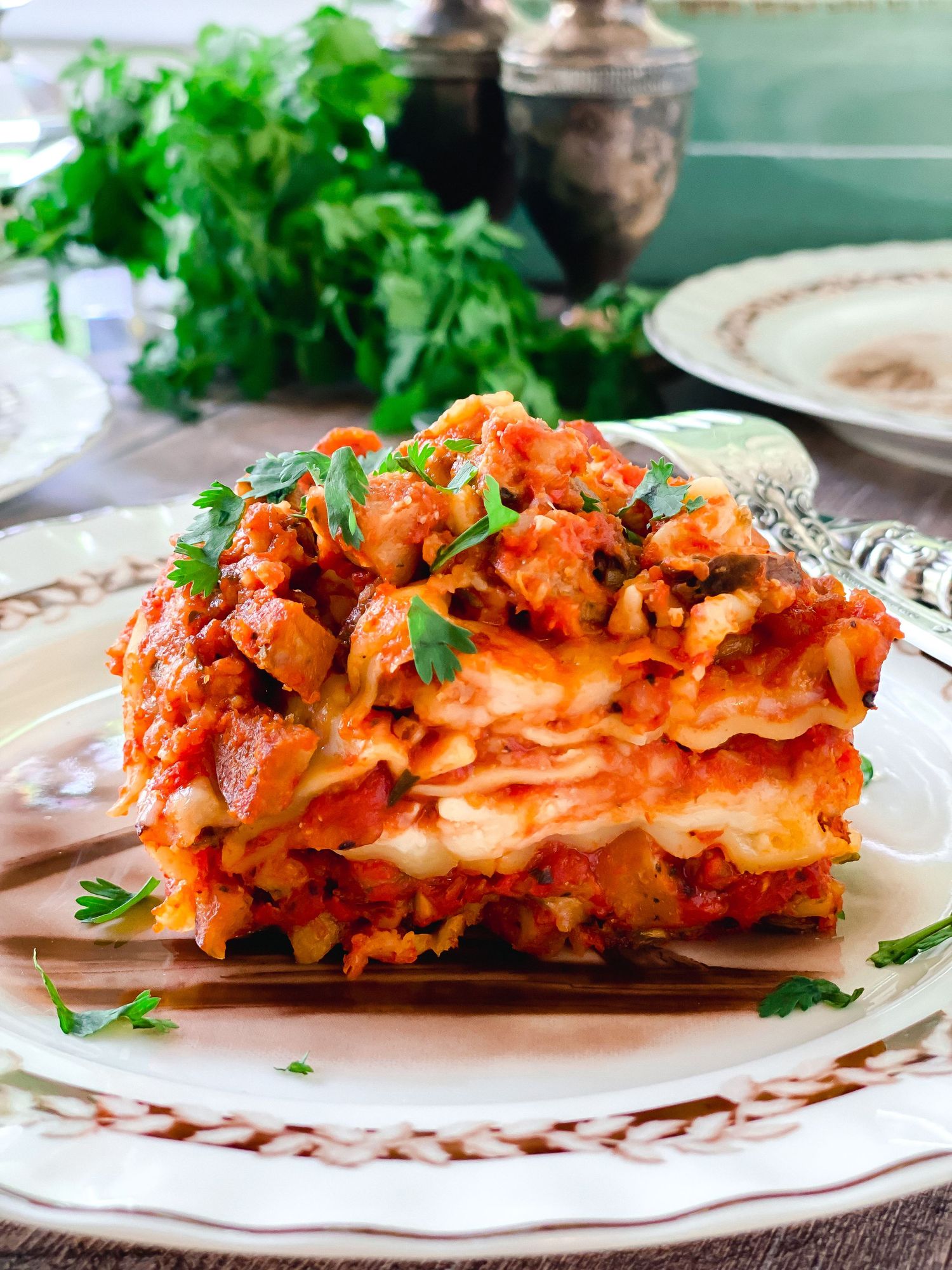 Layered lasagna with melted cheese and tomato sauce garnished with fresh herbs.