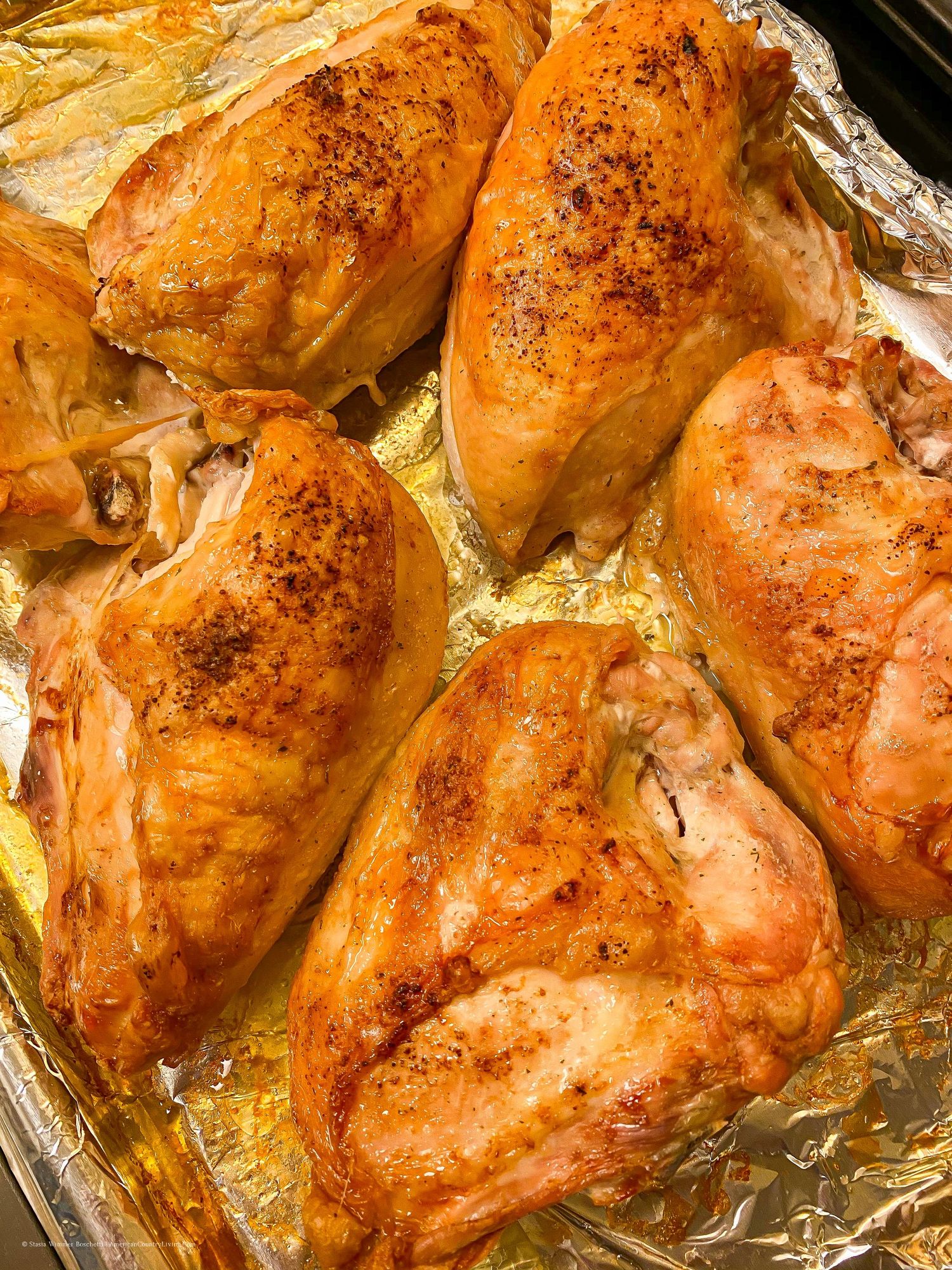 Golden brown roasted chicken pieces with crispy skin on aluminum foil.