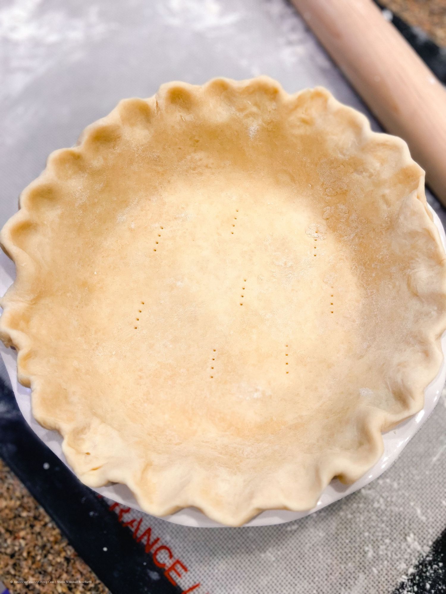 Pie crust with perfectly crimped edges placed in a ceramic pie dish.