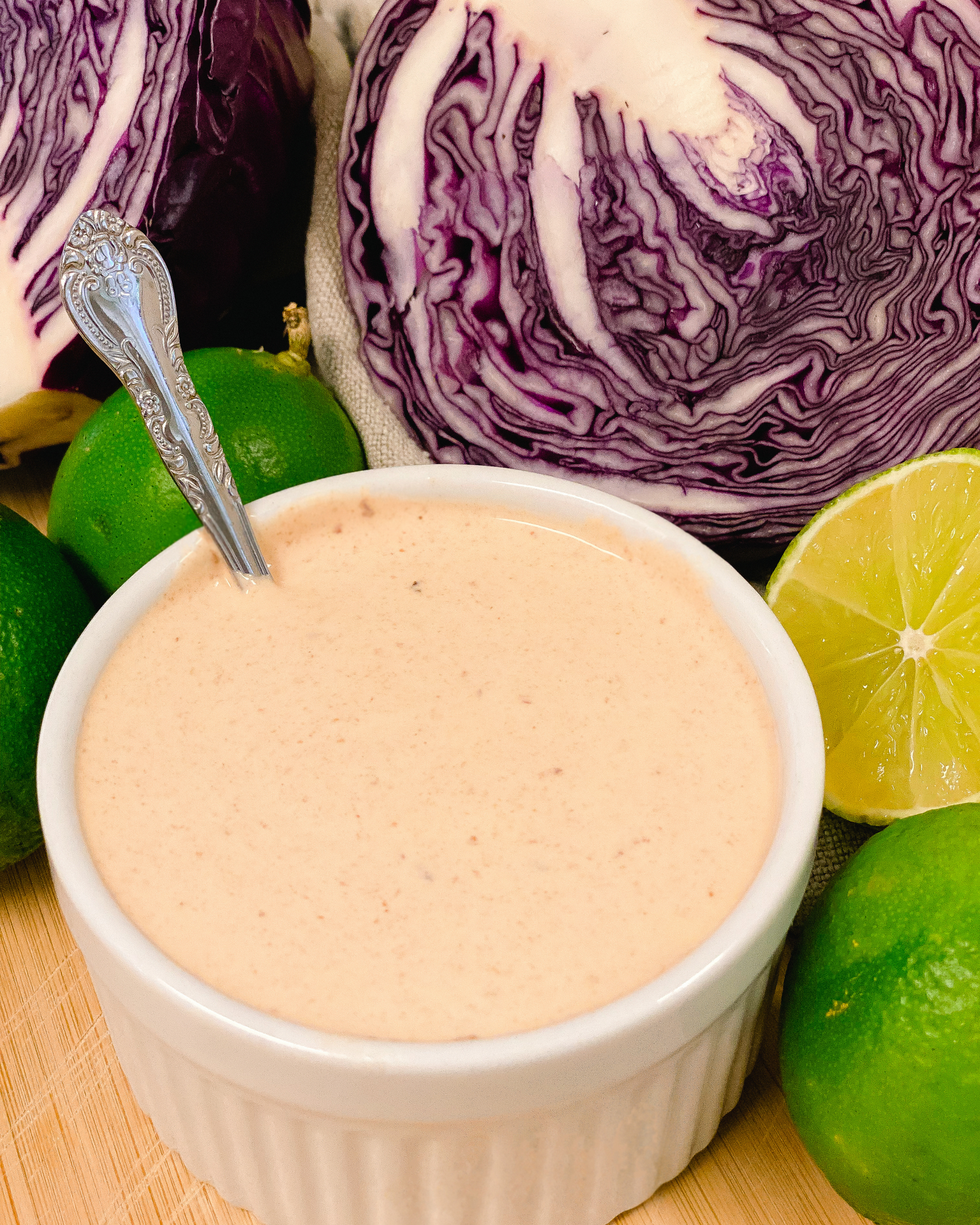 Close-up of pink sauce in a white bowl with red cabbage and citrus ingredients.