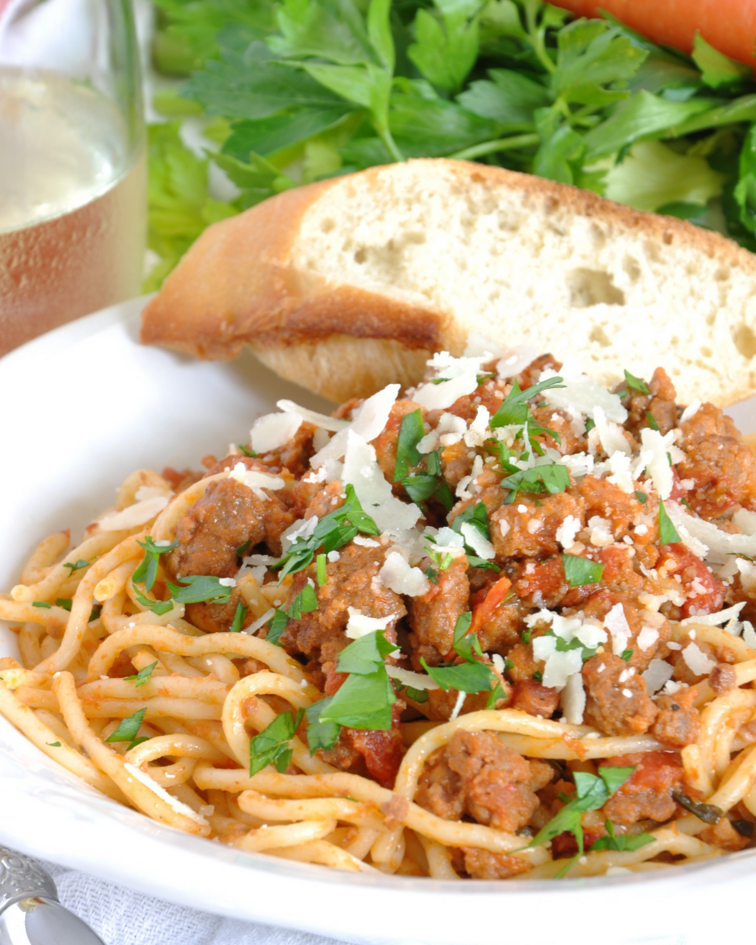 Spaghetti pasta dish topped with meat sauce, fresh herbs and grated cheese.