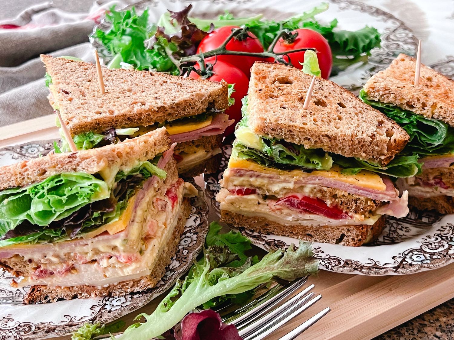 Fresh deli sandwiches with lettuce and tomatoes arranged on serving platters.