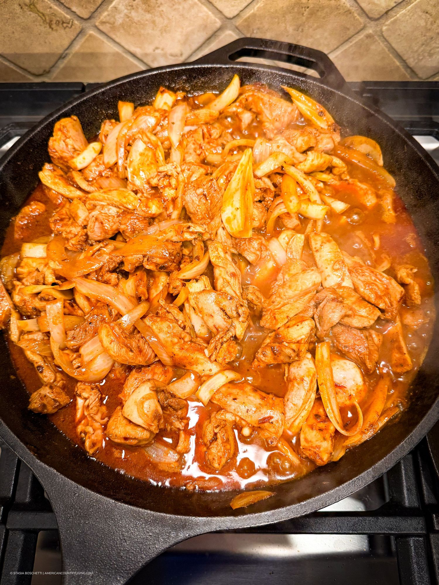 Cast iron skillet with spicy Korean bulgogi stir-fry featuring marinated meat and caramelized onions in rich red sauce.