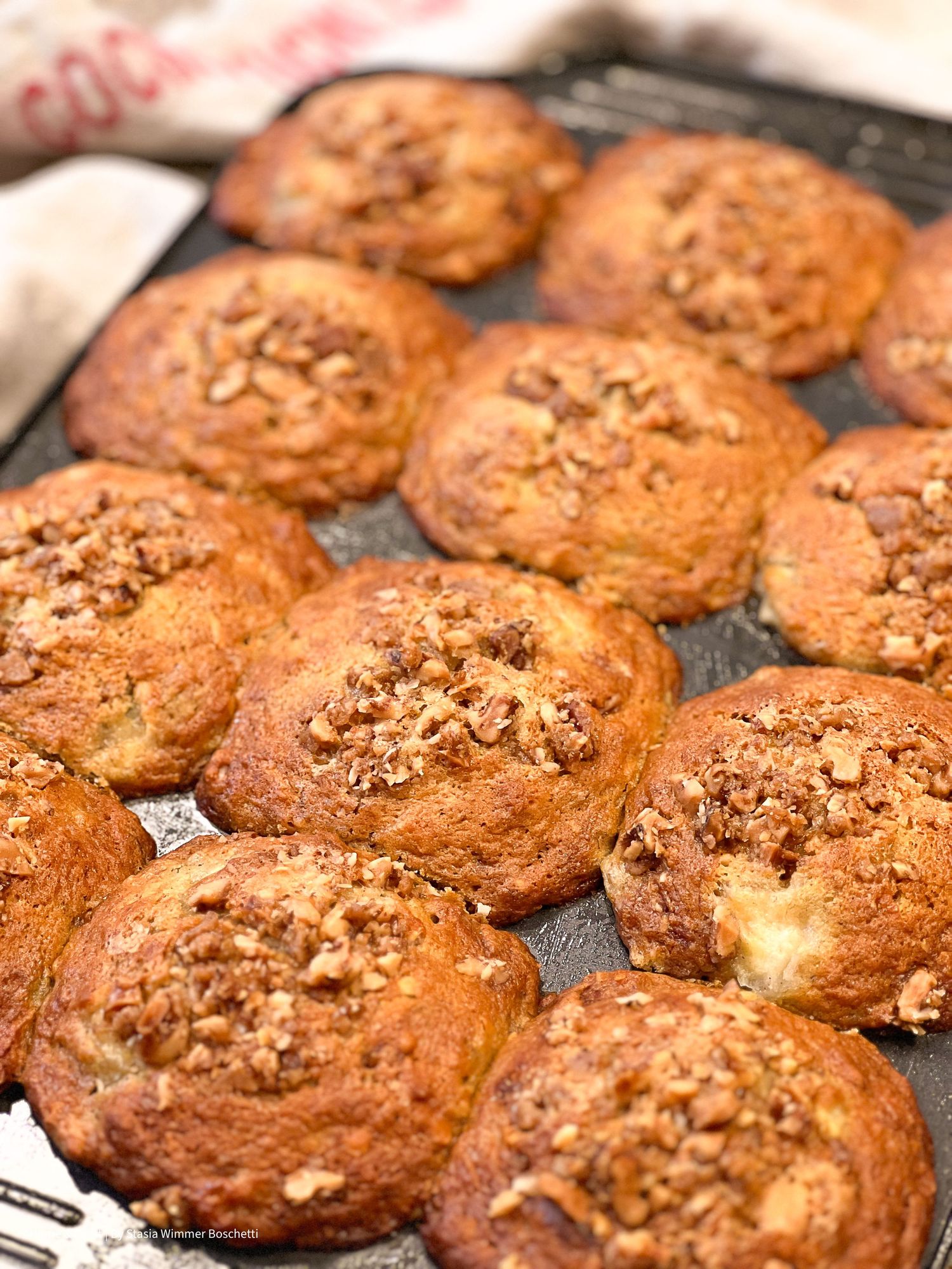 Golden brown muffins topped with nuts arranged on a baking sheet.