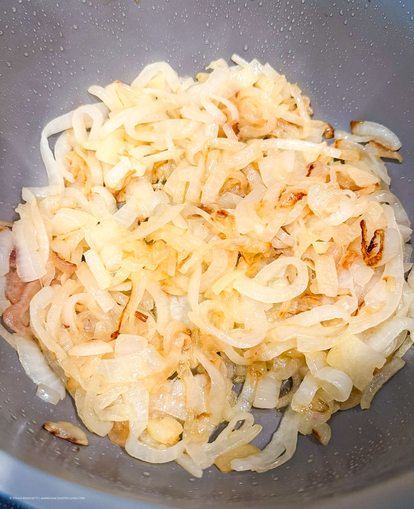 Sautéed caramelized onions cooked to golden perfection in a stainless steel pan.